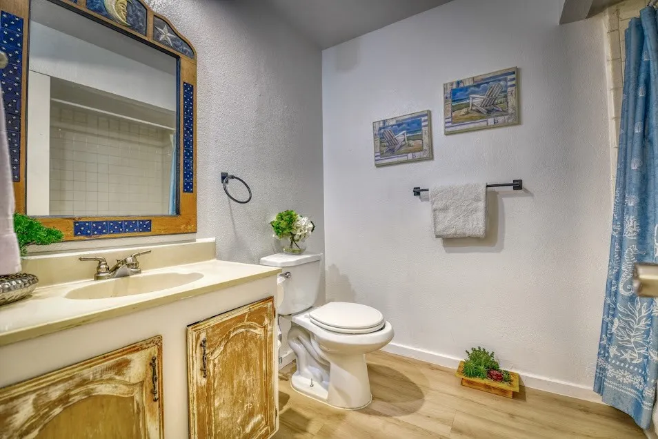 Bathroom featuring a single vanity with an integrated sink, dual-handle faucet, and distressed wood-finish cabinetry