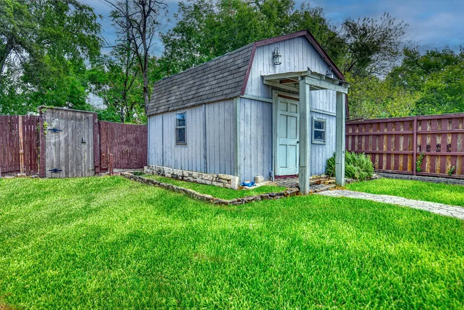 Detached shed with gambrel roof, covered porch entrance, and fenced perimeter