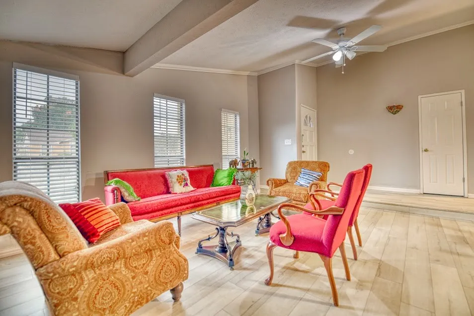 Vaulted ceiling with a ceiling fan, wood-finish flooring, multiple windows with blinds, and white trim molding
