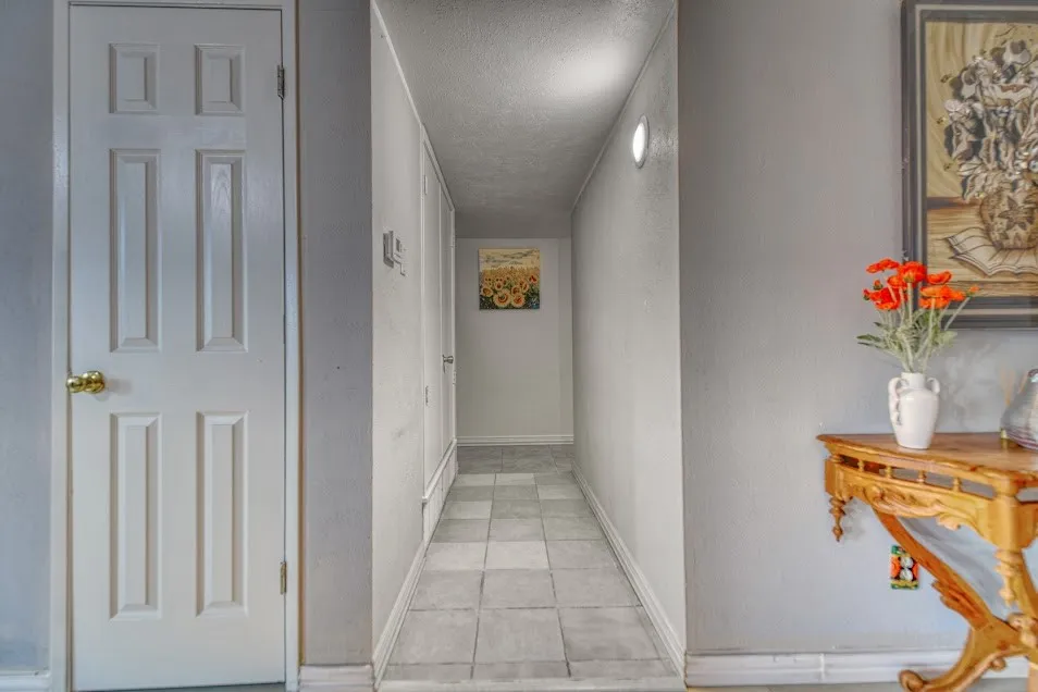 Tile flooring, interior paneled door, wall-mounted light fixture, carved wood console table