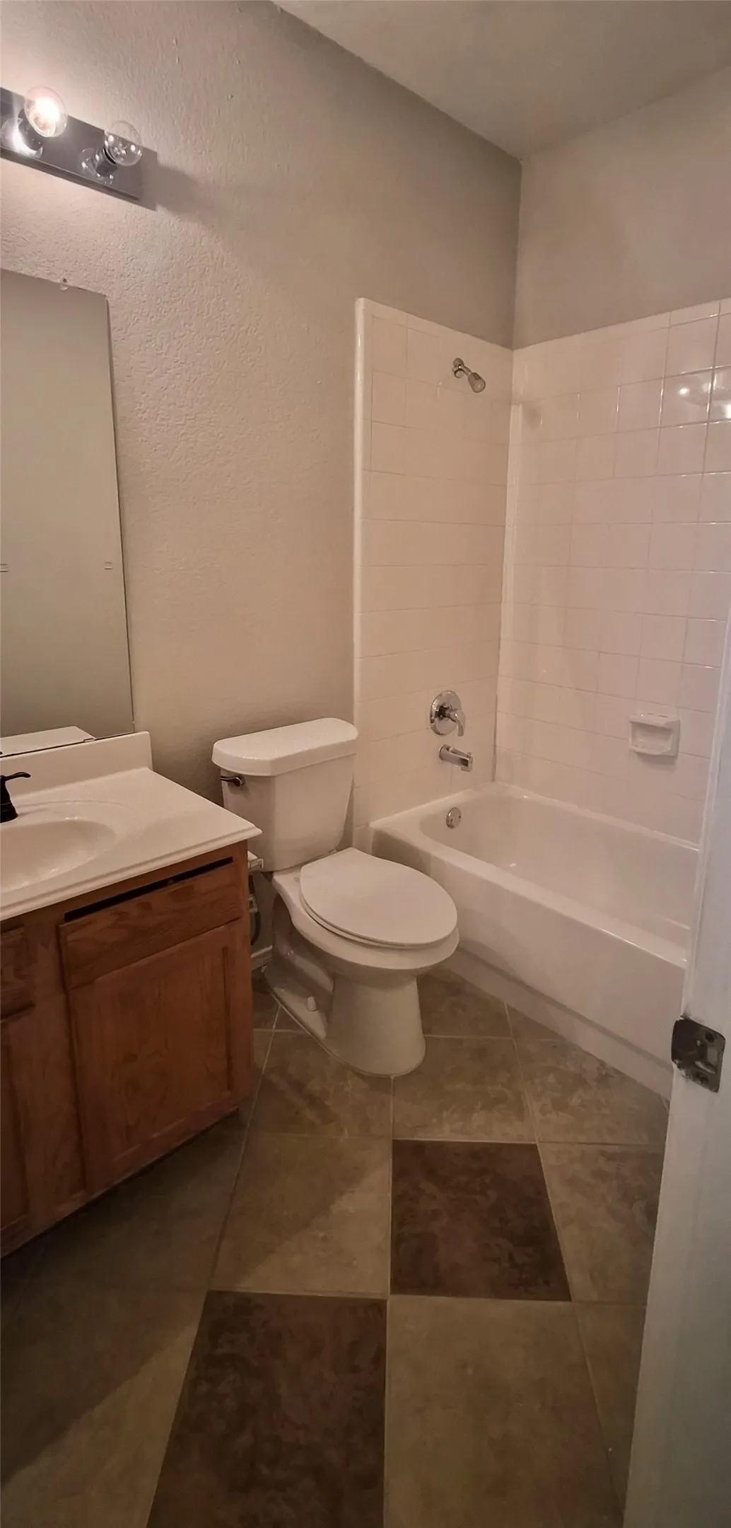 Bathroom featuring a vanity with an integrated sink, a toilet, and a bathtub with a shower