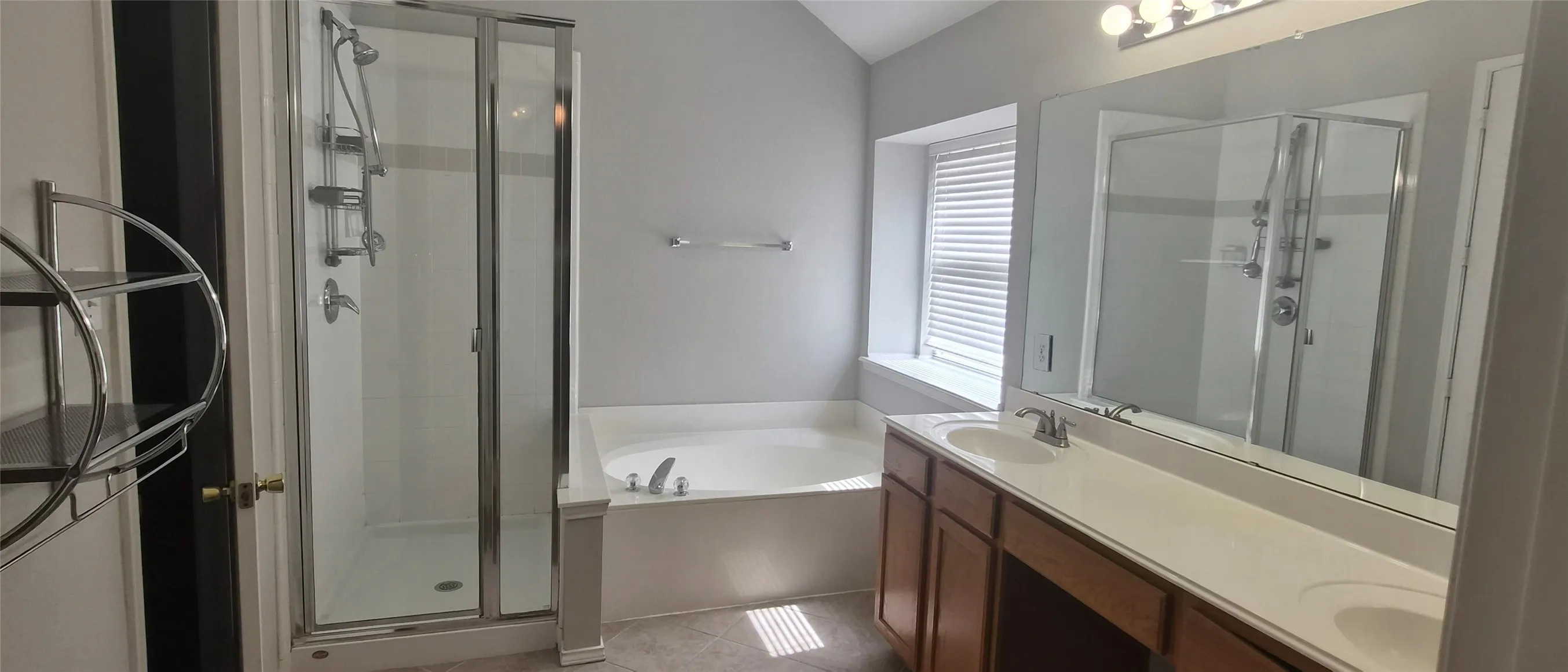 Integrated shower with glass enclosure, built-in soaking tub, dual vanity with undermount sinks, wood-finish cabinetry, and overhead lighting