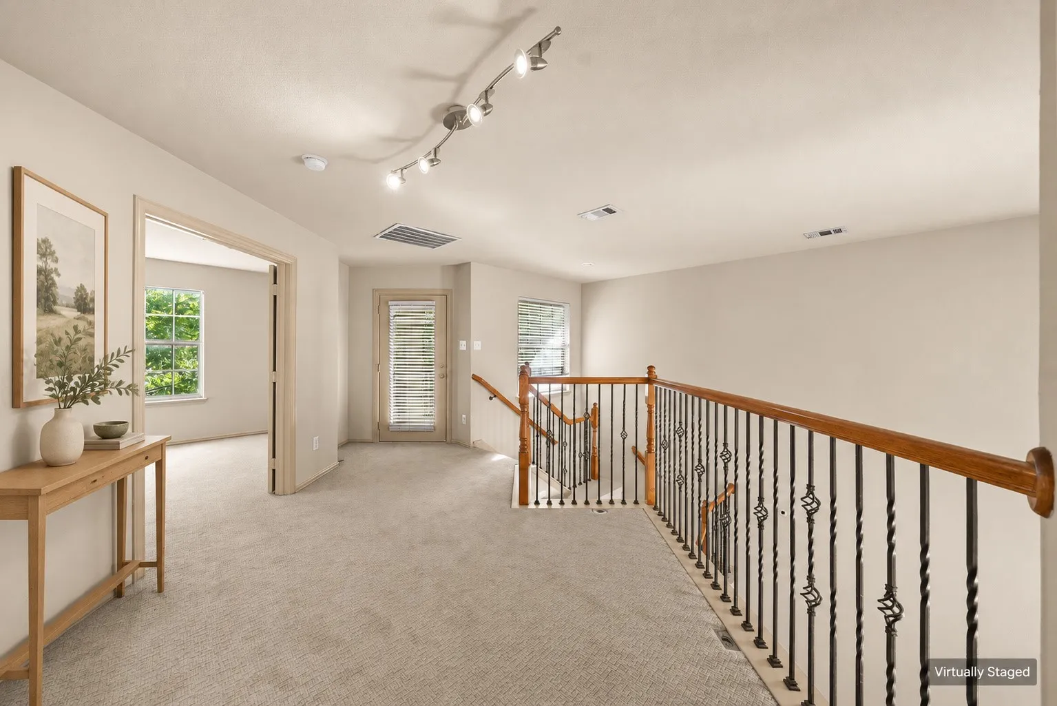 Loft area featuring neutral carpet, track lighting, and a wrought iron and wood-finish banister