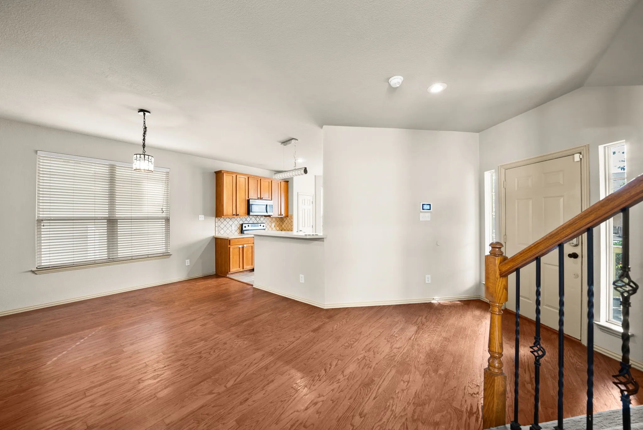 Wood-finish flooring throughout, with a kitchen featuring wood cabinetry and stainless steel appliances