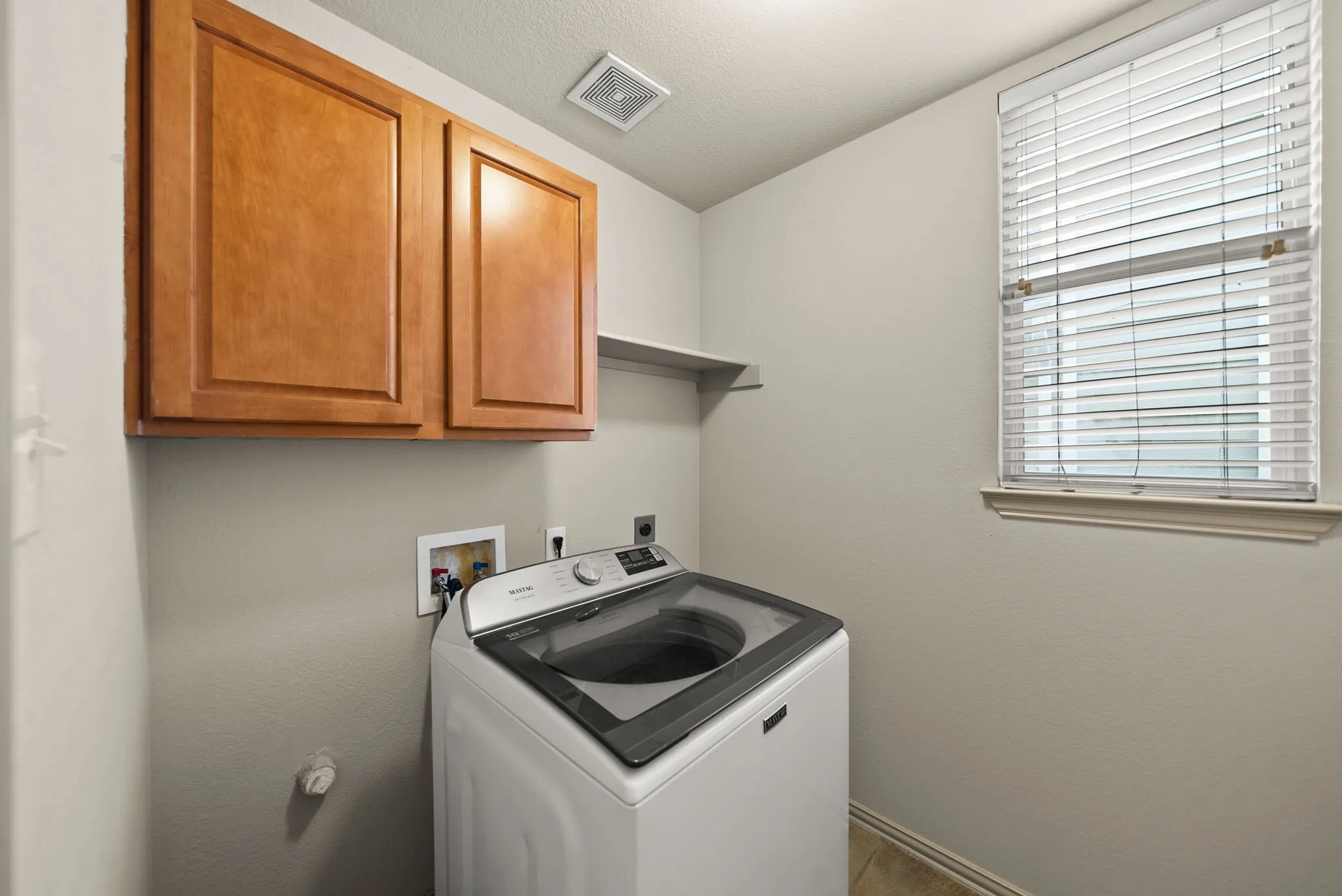 Utility space featuring upper cabinetry, a built-in wall shelf, and tiled flooring