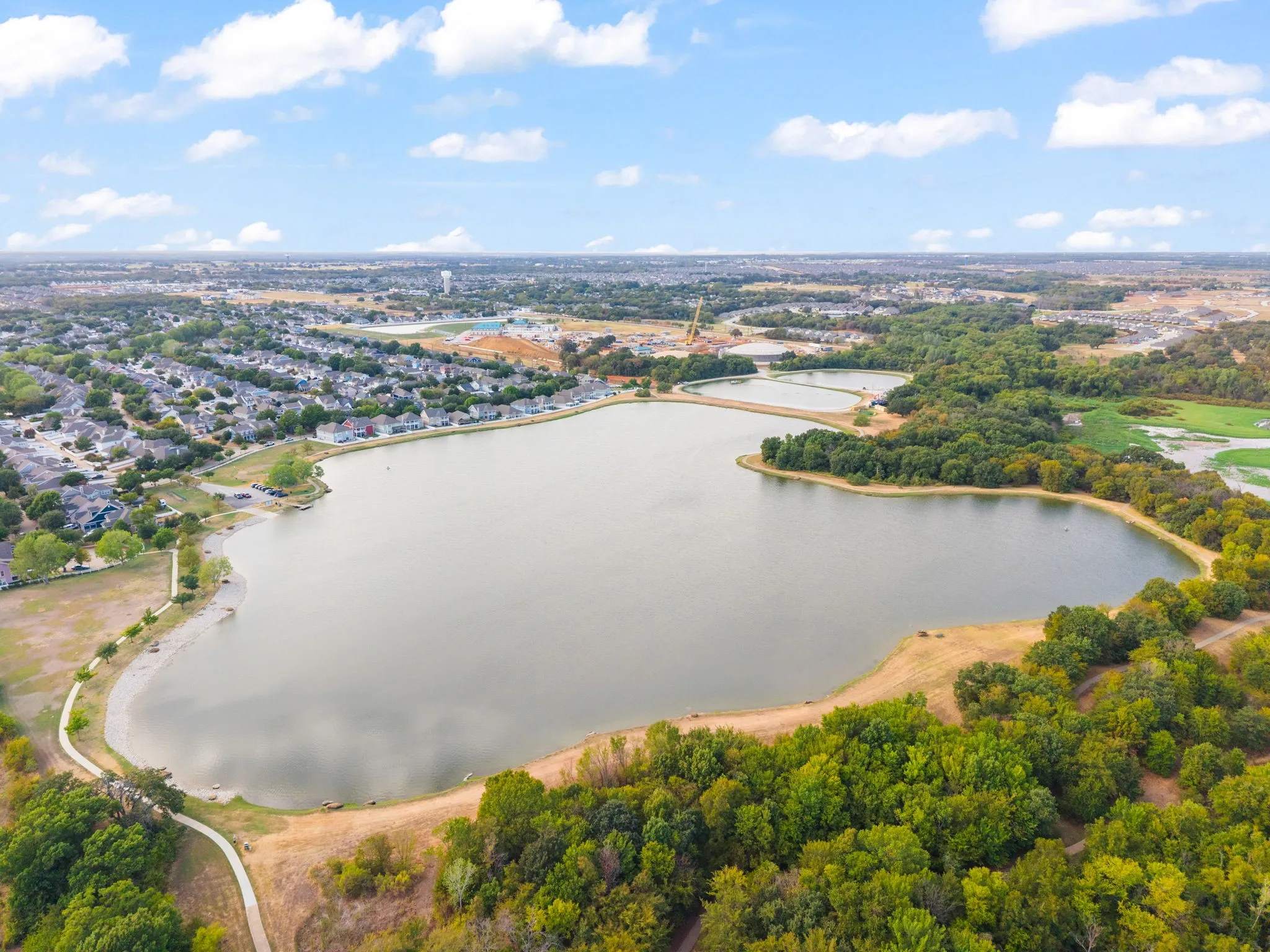 Expansive lake with surrounding green spaces, mature trees, and residential areas