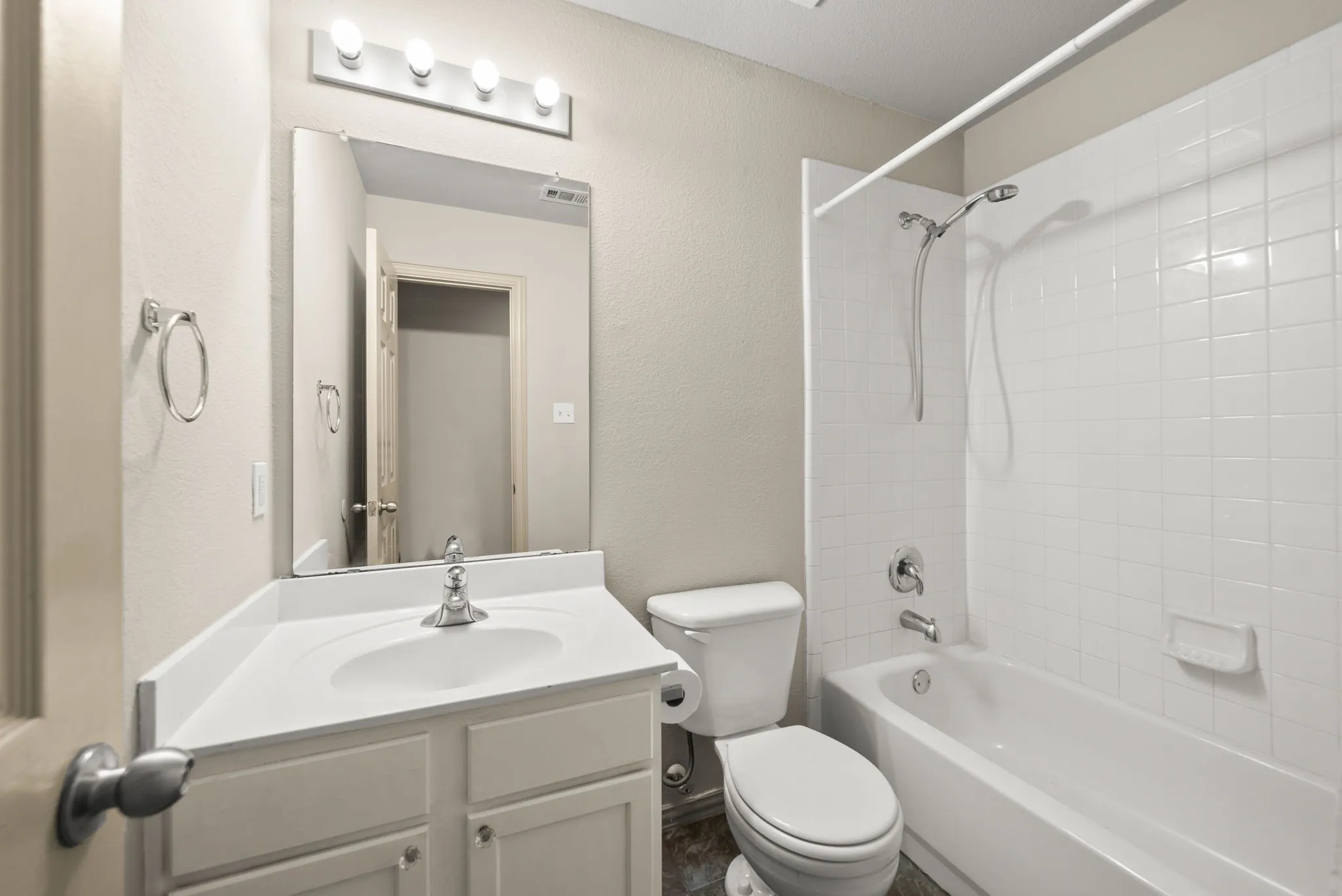 Vanity with an integrated sink, polished chrome faucet, and a large wall-mounted mirror