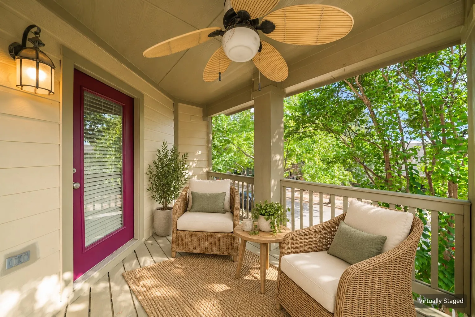 Covered outdoor patio featuring a ceiling fan with natural-finish blades, a vibrant magenta-framed glass panel door, and an exterior wall lantern