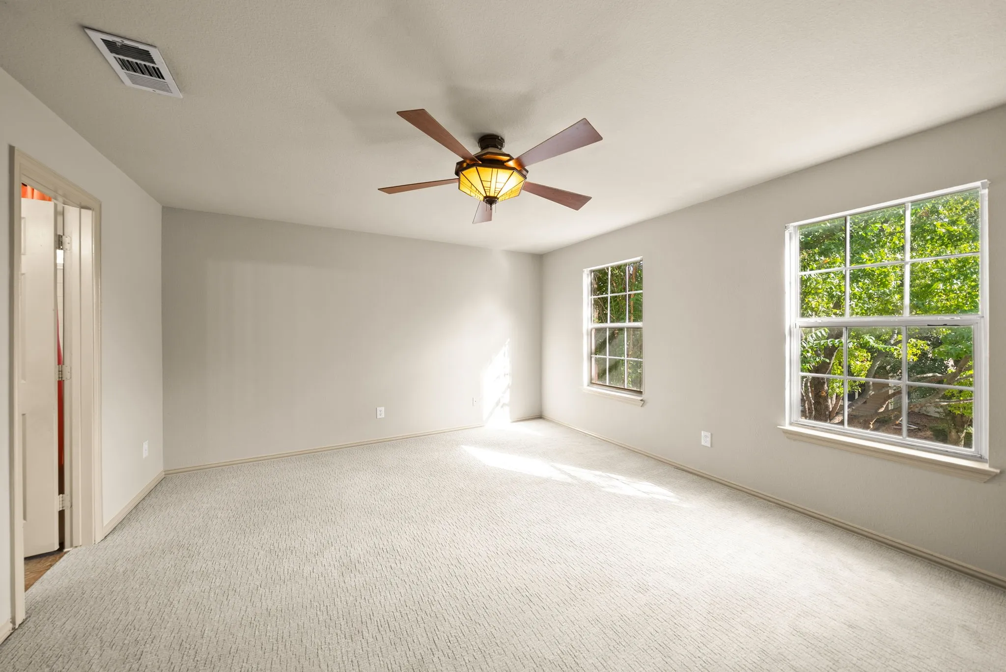 Neutral wall finishes, carpeted flooring, two window openings, and a ceiling fan with integrated lighting