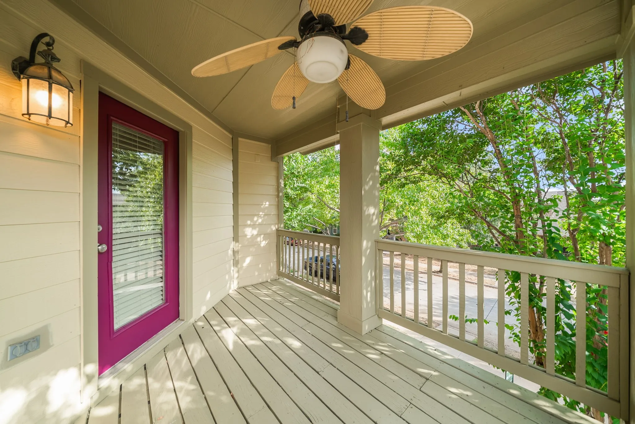 Covered porch featuring a ceiling fan, outdoor wall lantern, and a magenta entry door