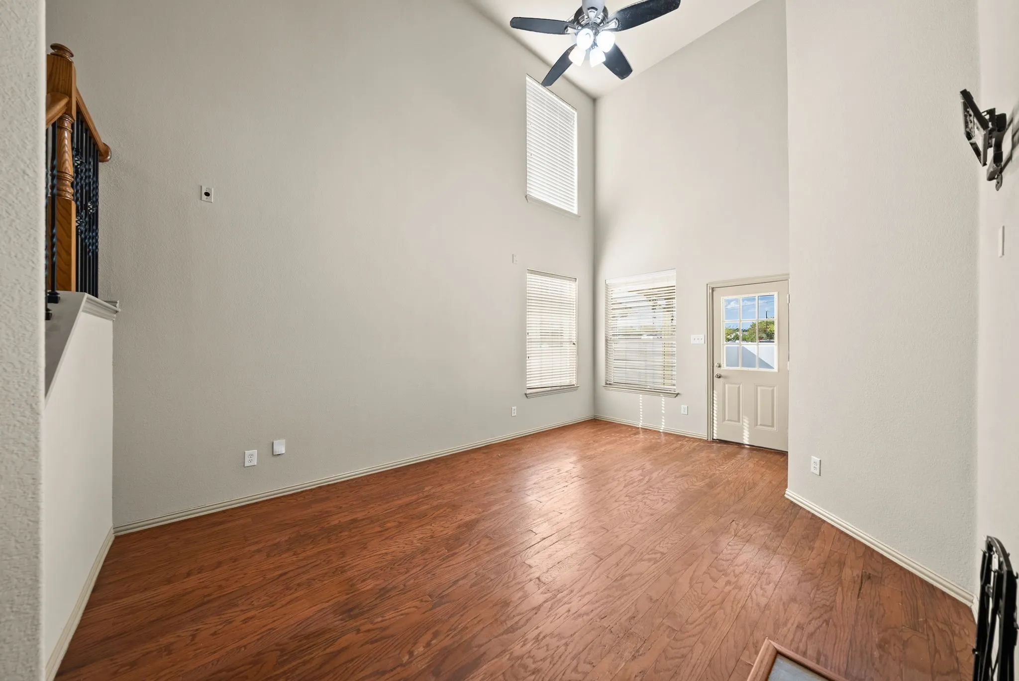 Vaulted ceilings, wood-finish flooring, ceiling fan, multiple windows, and a glass-paneled exterior door