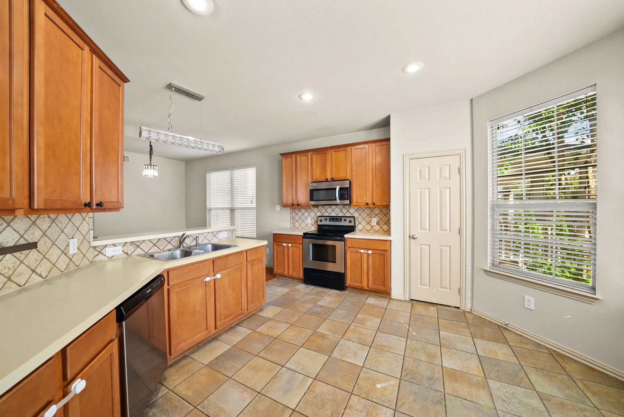 Kitchen featuring wood cabinetry, stainless steel appliances, tile flooring, and a tile backsplash