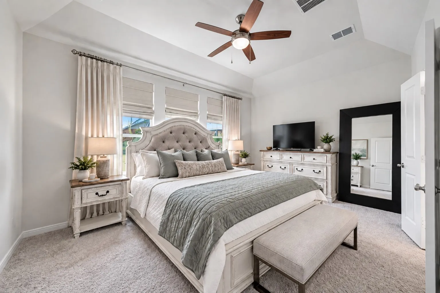 Vaulted ceiling with a ceiling fan, three windows with blinds, and light-colored carpeting