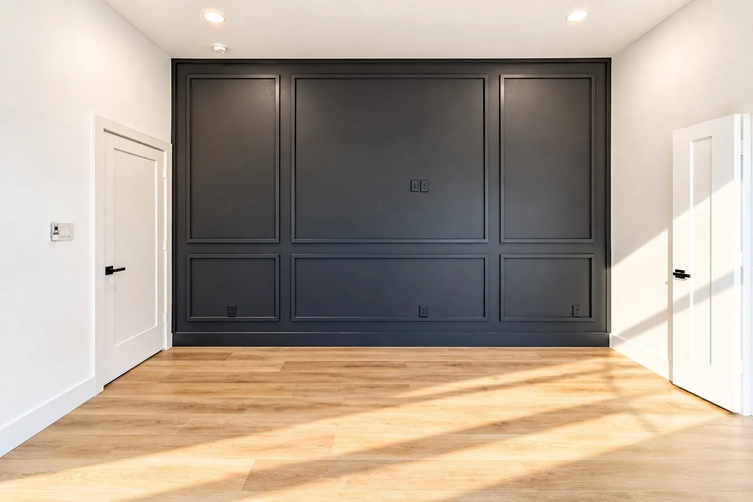 Accent wall with panel molding, wood-finish flooring, recessed lighting, and white interior doors with black hardware