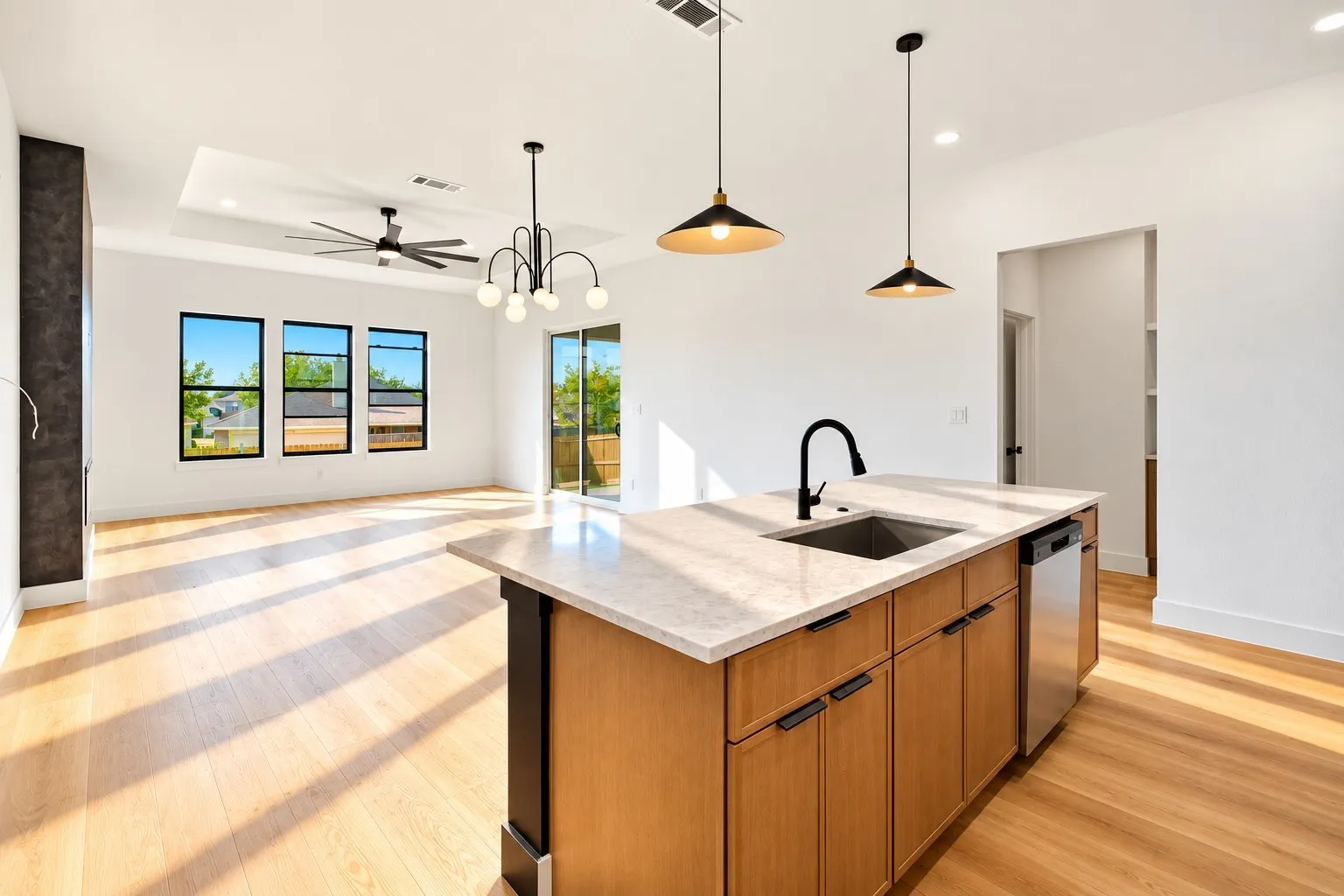 Central kitchen island with an undermount sink, light-toned countertop, and integrated dishwasher