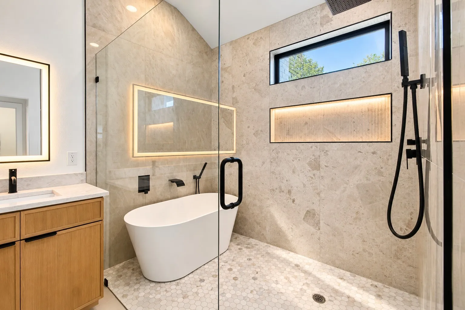 Integrated wet room with a freestanding soaking tub, hex tile flooring, and a glass shower enclosure