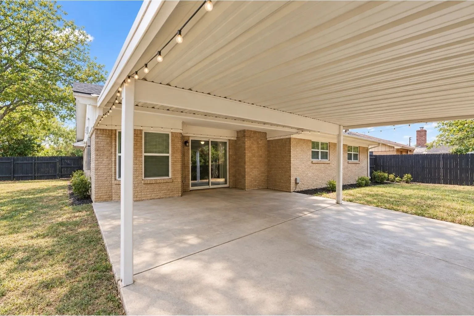 Spacious covered patio with string lighting, a concrete surface, and direct access to interior via sliding glass doors