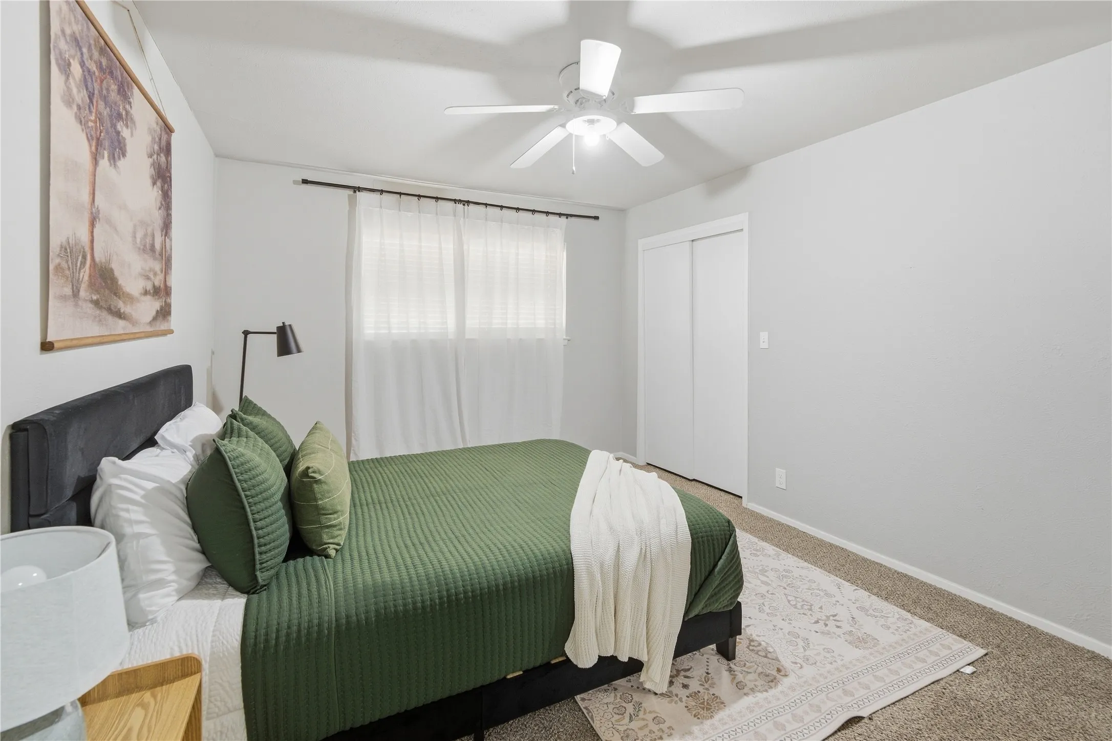 Wall-to-wall carpeting, ceiling fan with integrated lighting, window with drapes and blinds, and a closet with sliding doors