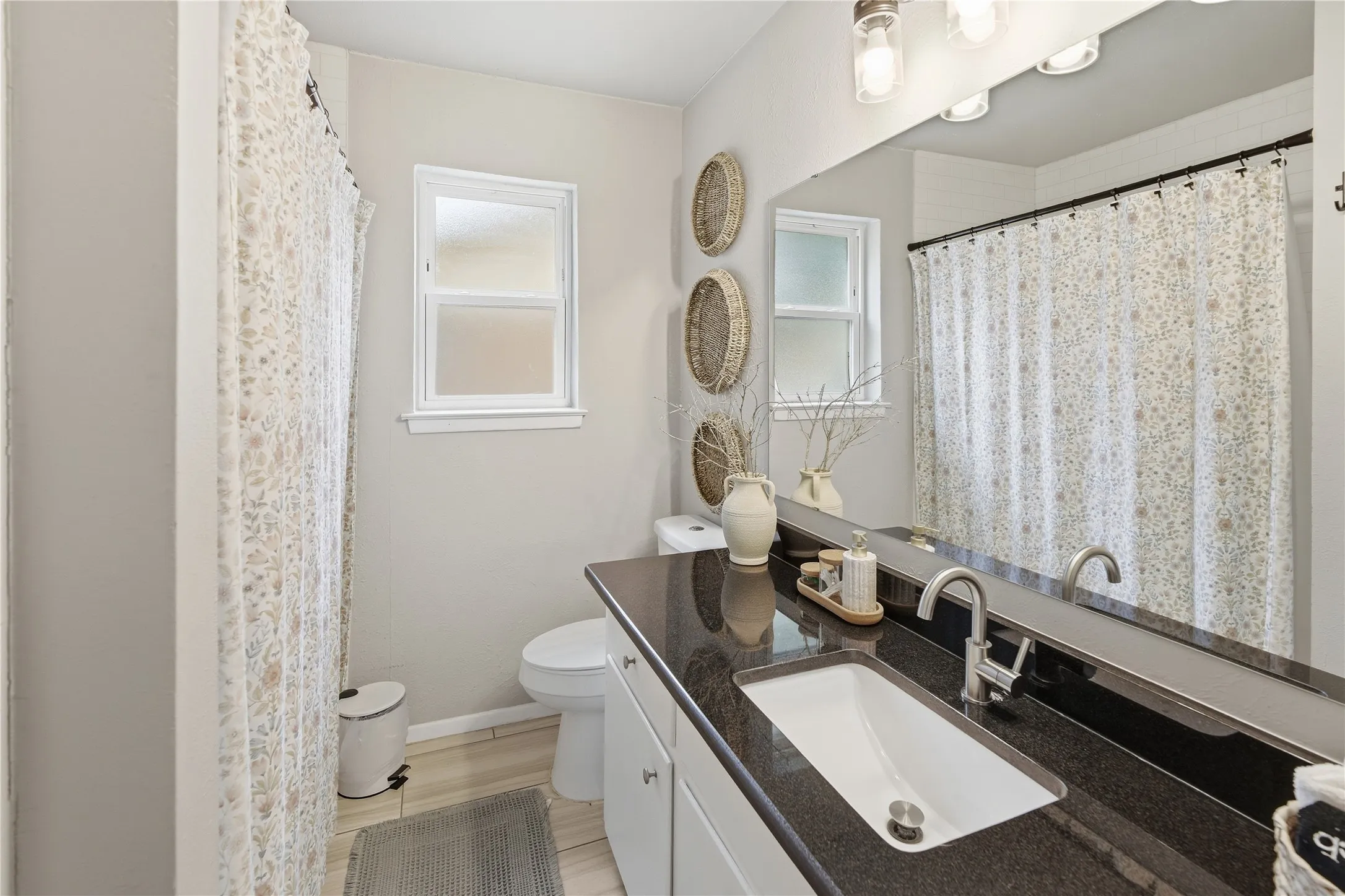 Single vanity with a dark countertop, undermount sink, and chrome faucet
