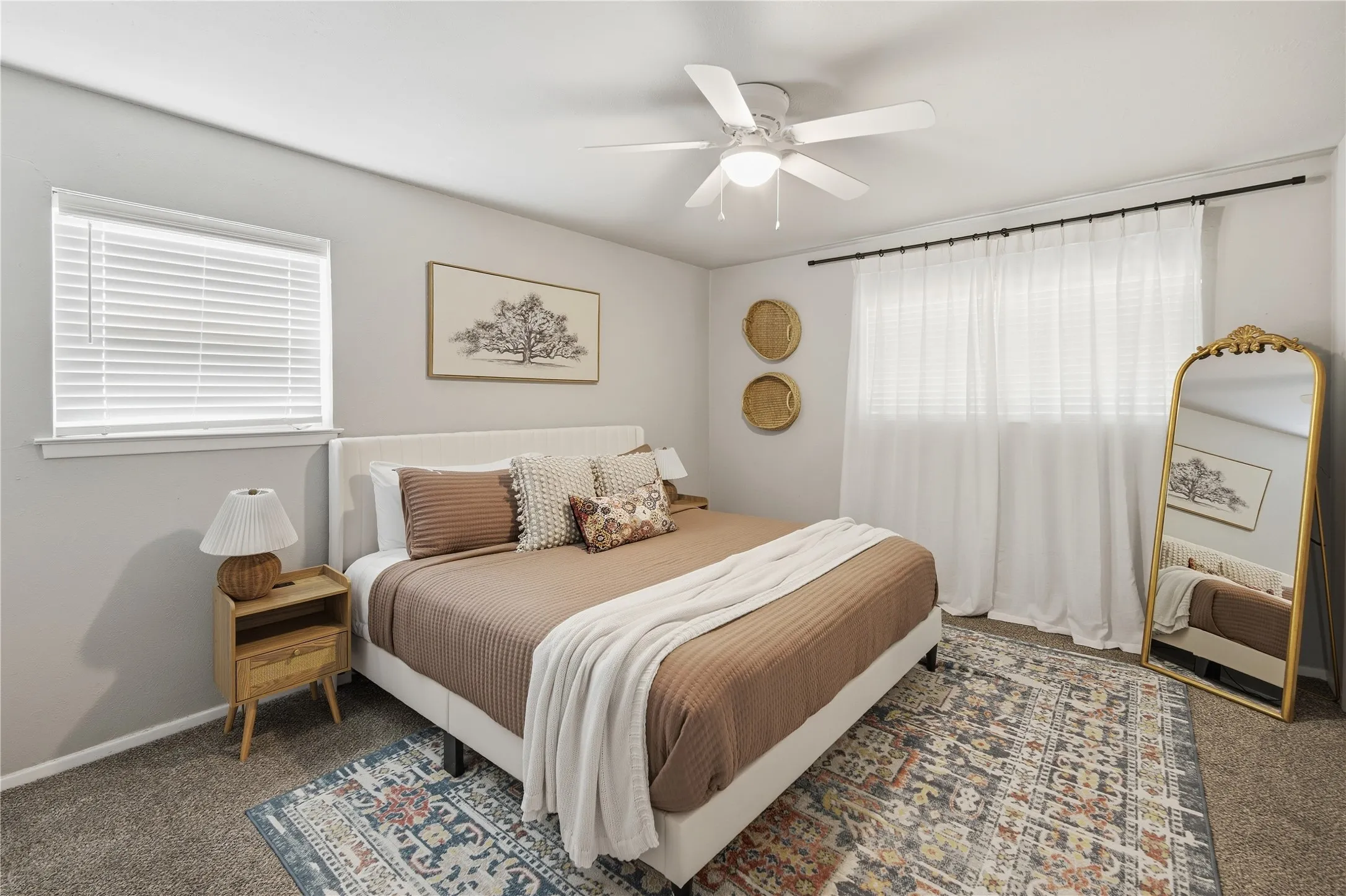 Recessed window with blinds, ceiling fan with light, upholstered headboard, and wall-to-wall carpeting