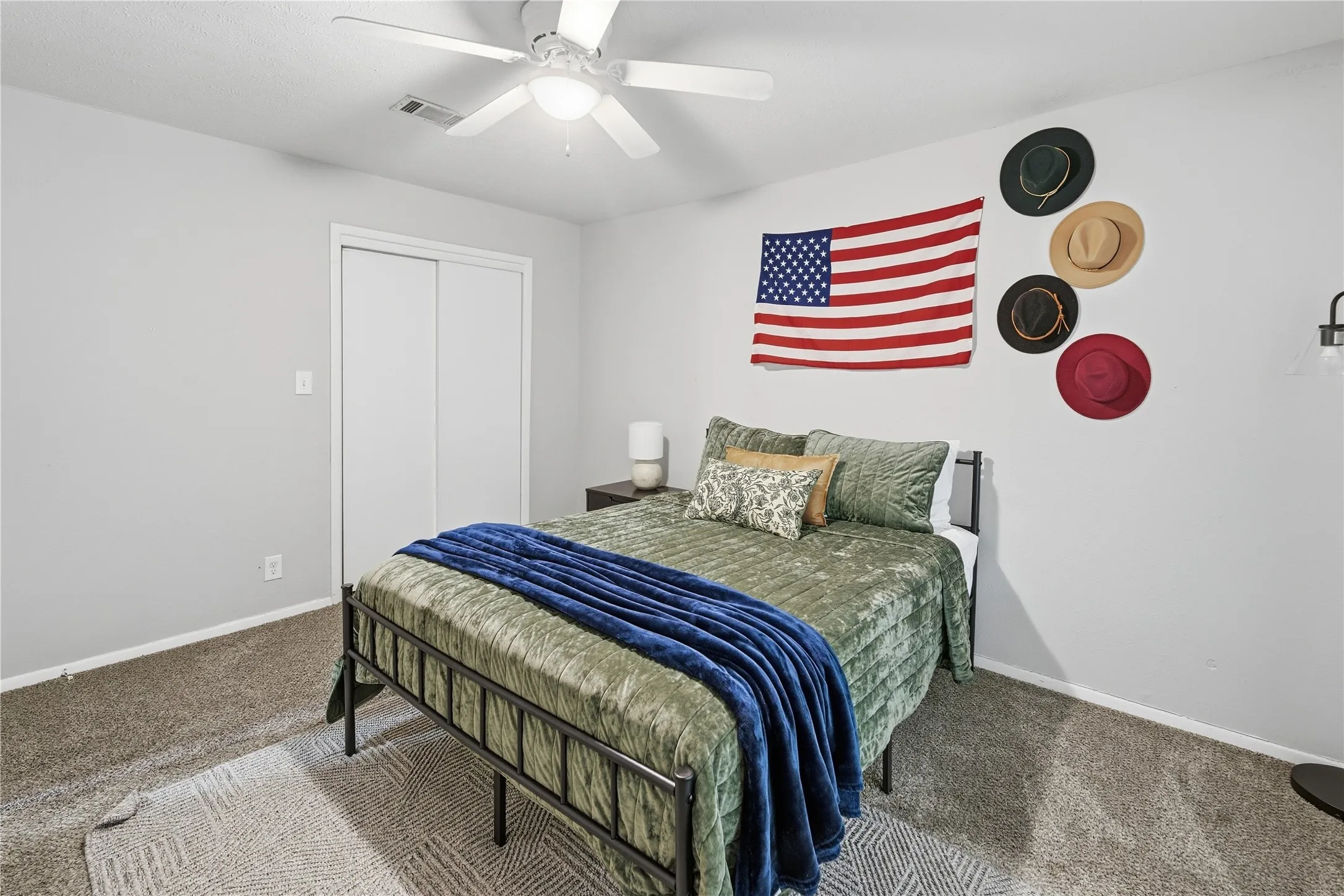 Carpeted flooring, white walls, ceiling fan, and sliding closet doors