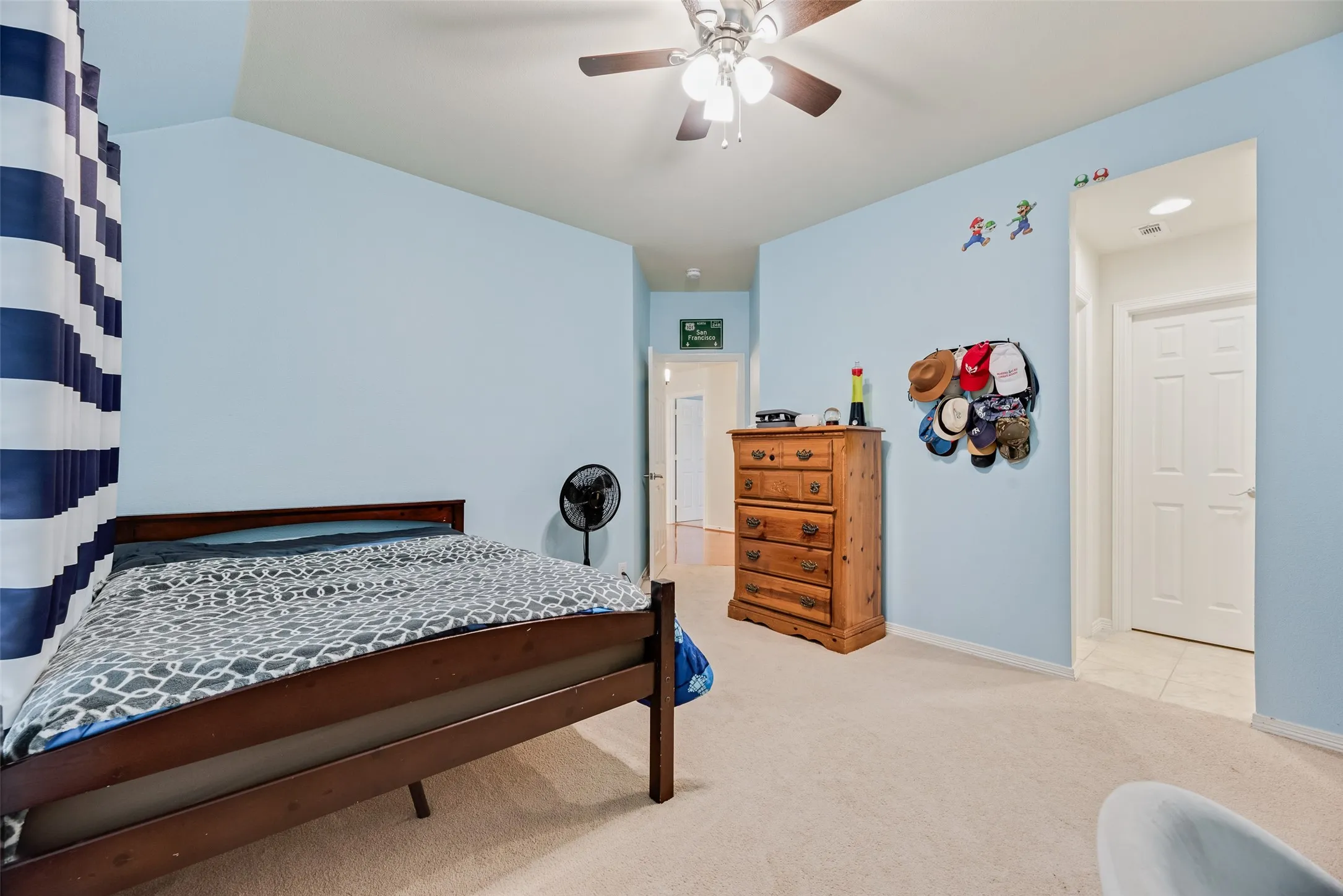 Vaulted ceiling with an attached ceiling fan, light-toned carpeting, and a white paneled door
