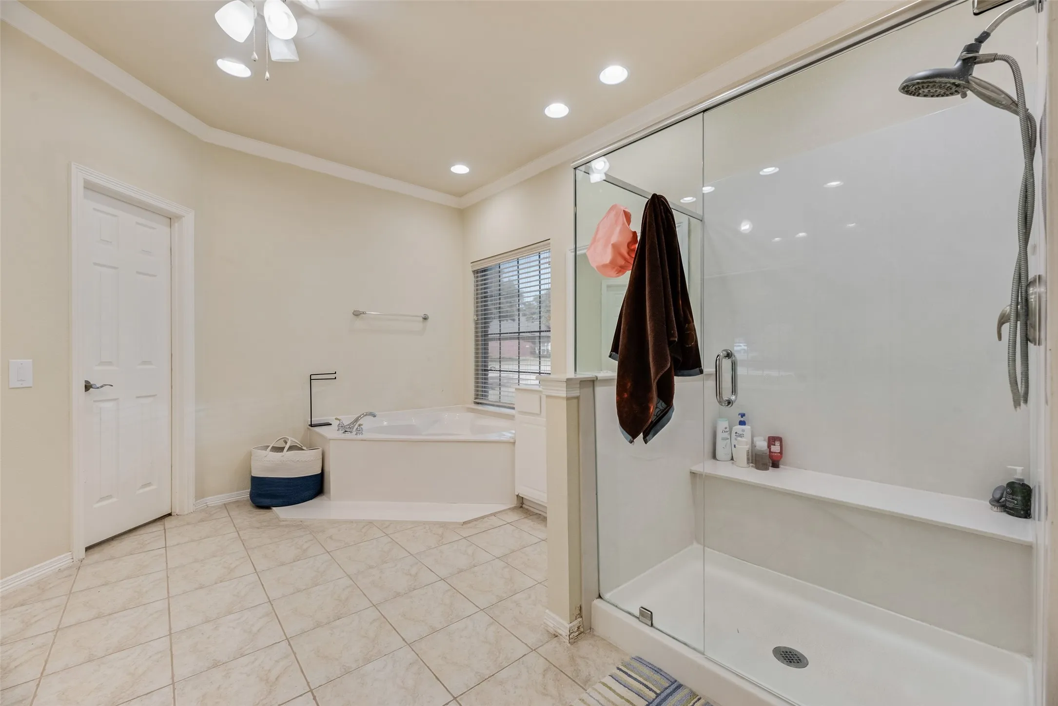 Spacious bathroom featuring a glass-enclosed shower, built-in shower bench, corner soaking tub, and tile flooring