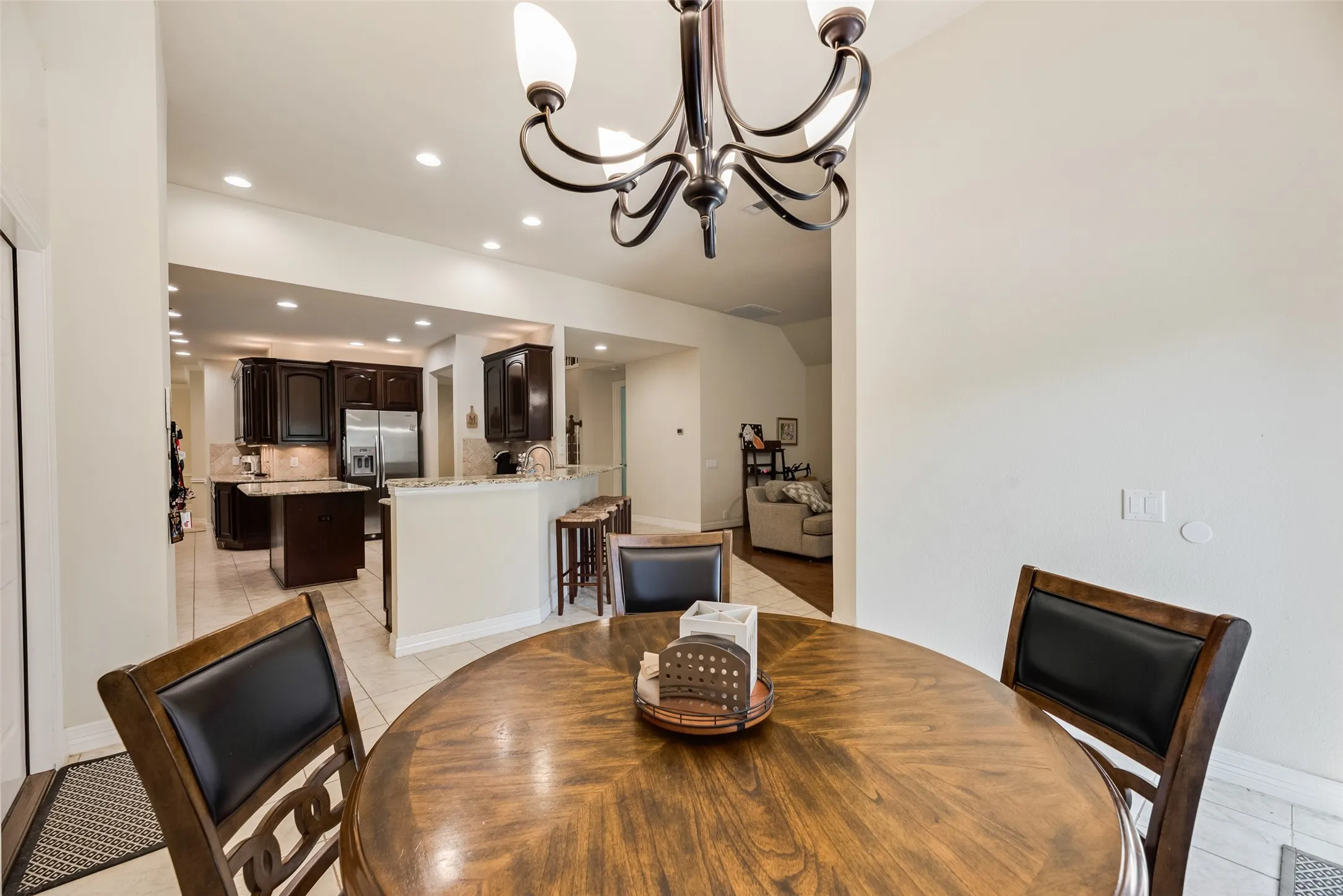 Recessed lighting, tiled flooring, dark wood-finish cabinetry, light-toned countertops, and a built-in kitchen island
