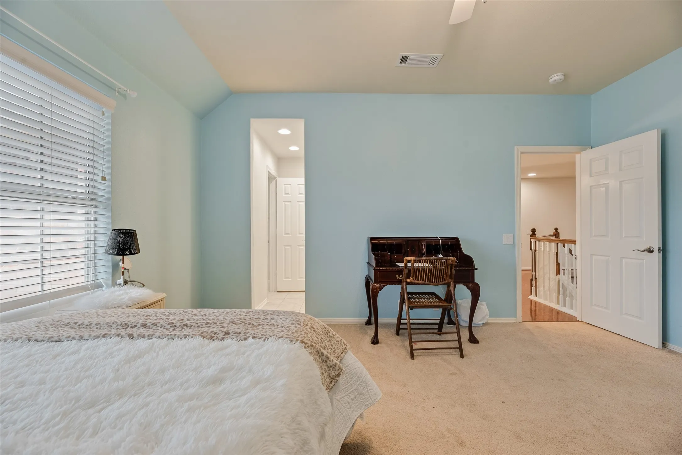 Neutral-toned carpeting, ceiling fan, window with blinds, and white paneled doors