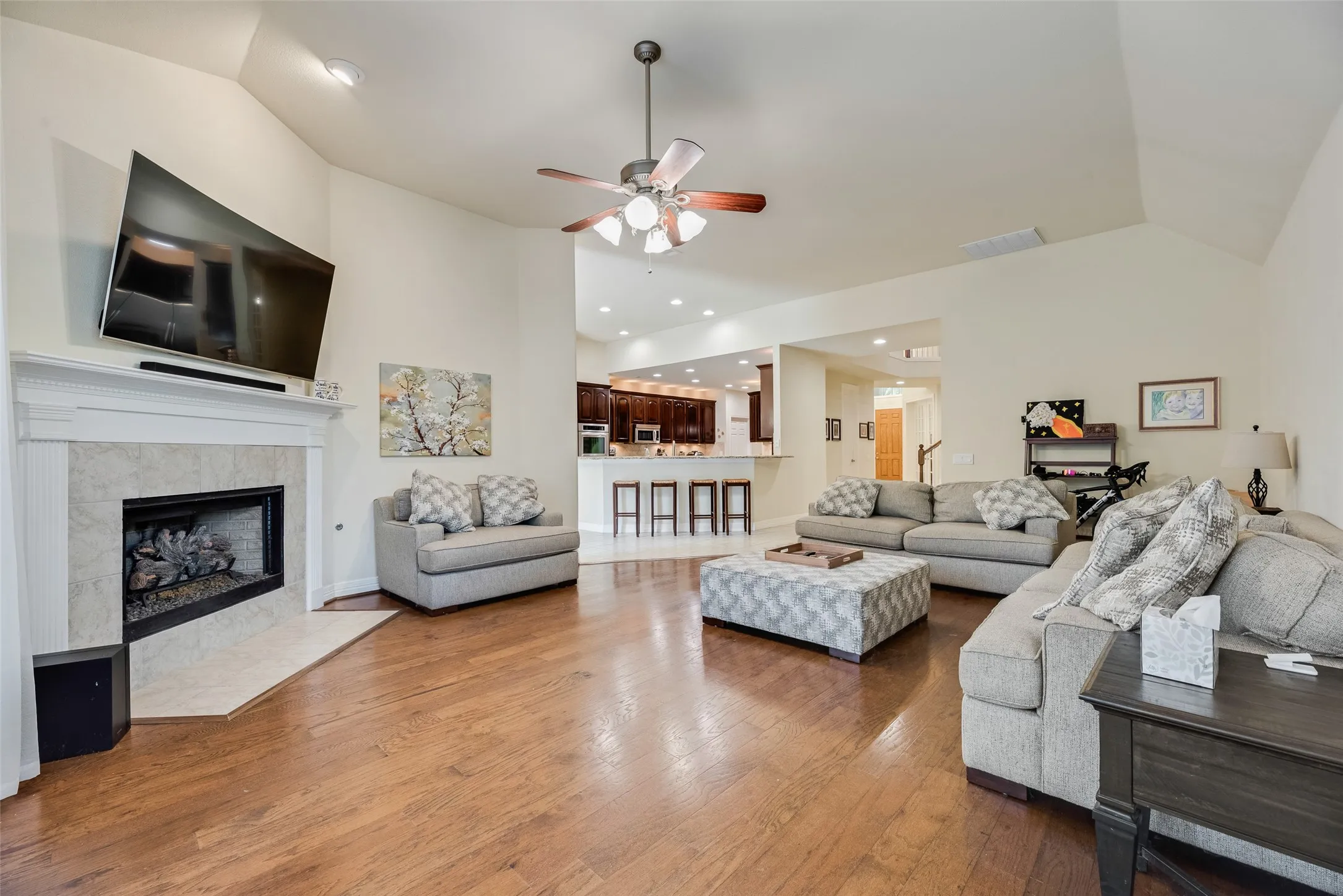 Vaulted ceilings, wood-finish flooring, and a fireplace with a tile surround