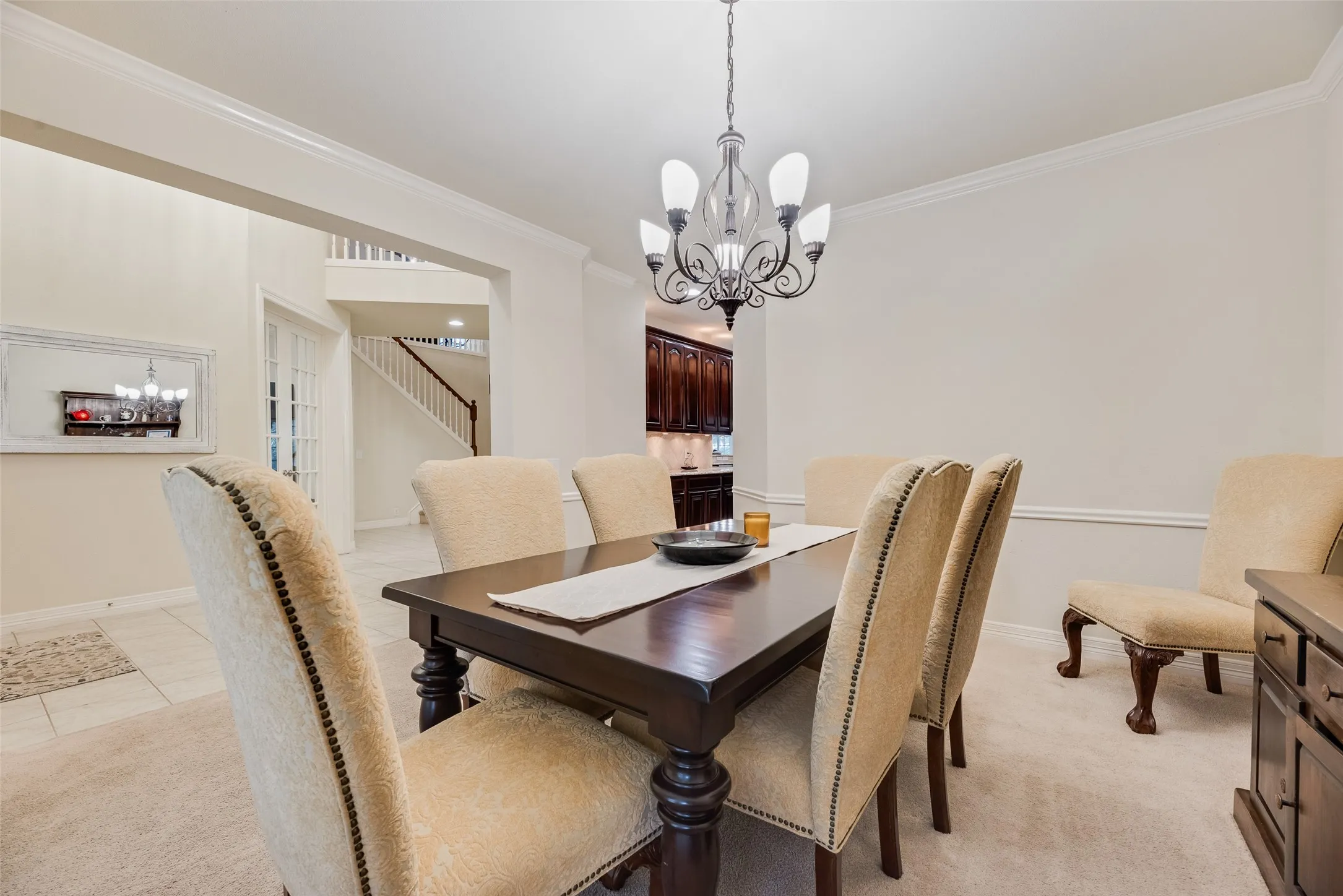 Formal dining space featuring crown molding, wall paneling, a chandelier, and carpet flooring