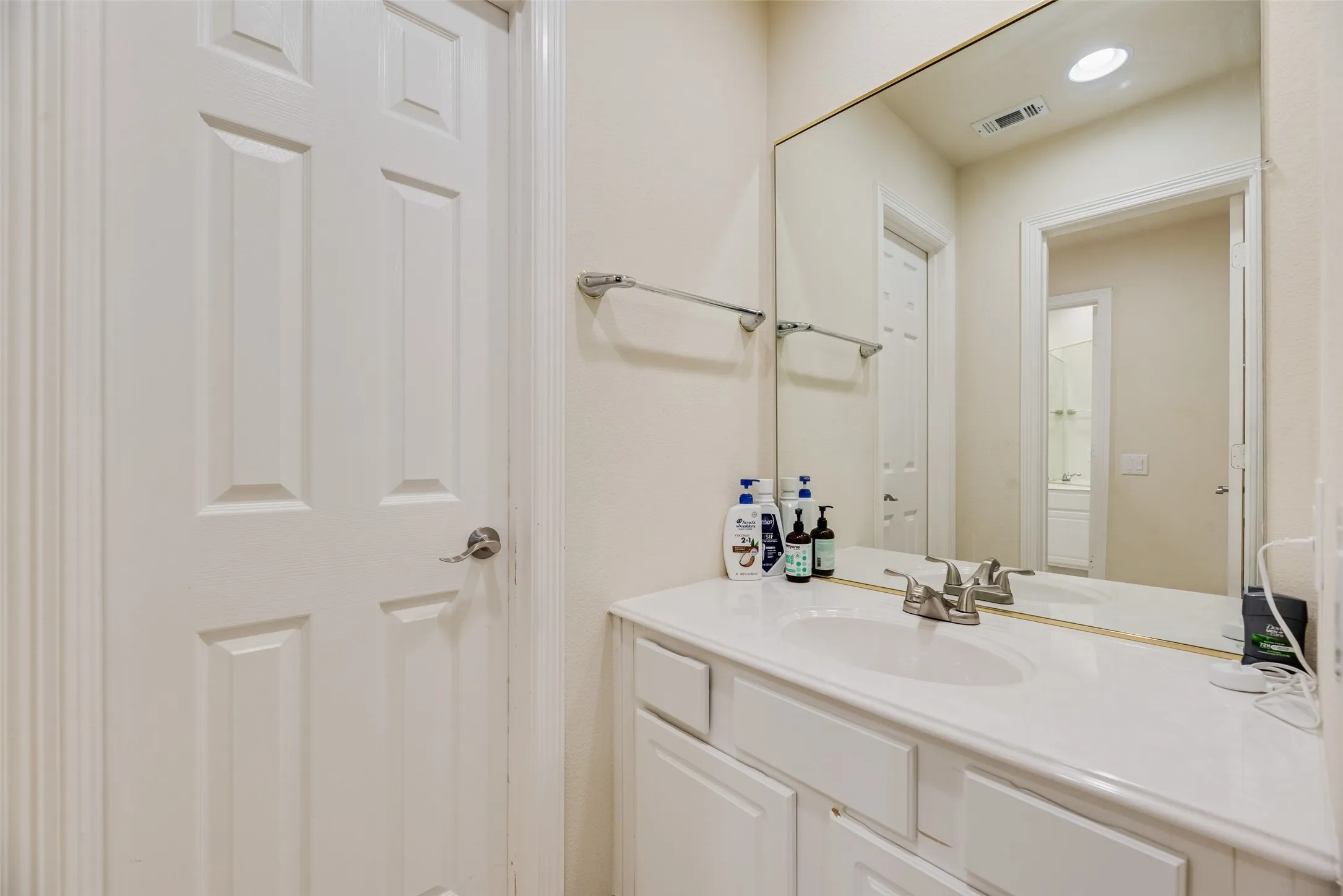 Vanity with an integrated sink, brushed nickel faucet, and a large wall-mounted mirror
