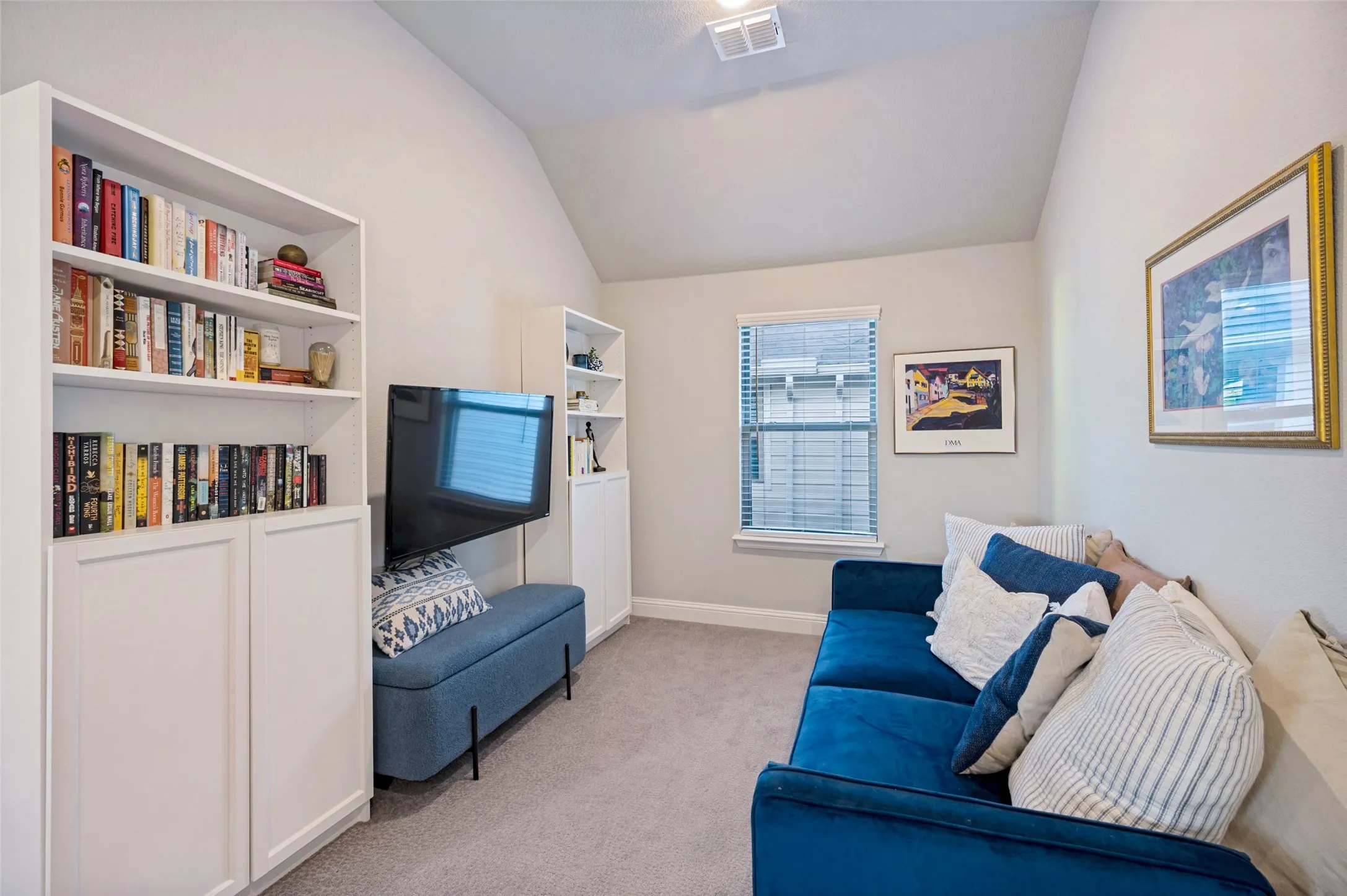 Primary room seating area features vaulted ceiling with an overhead light fixture, window with blinds.