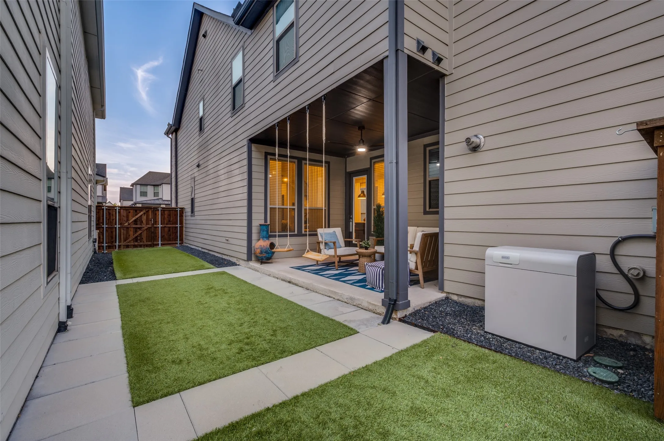 Covered patio with integrated ceiling fan, concrete flooring, artificial turf and BASE POWER Whole-Home Battery Backup.