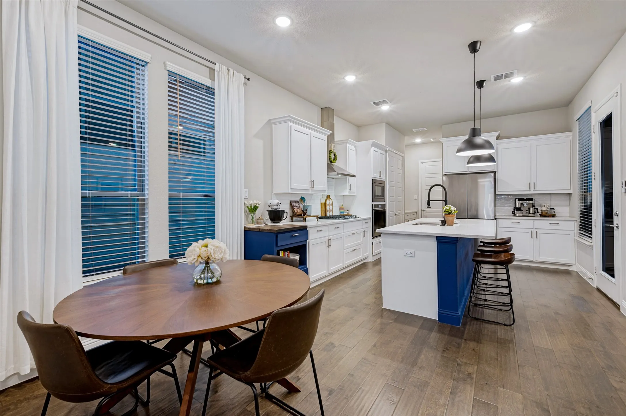 Open-concept kitchen featuring wood-finish flooring, recessed lighting, a kitchen island with seating, and white cabinetry