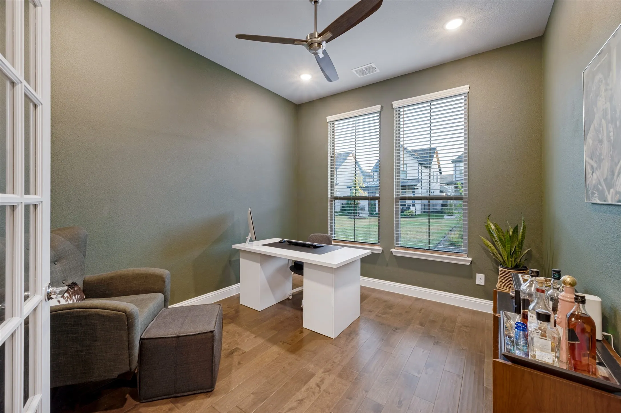 Wood-finish flooring, two large windows with blinds, recessed lighting, and a ceiling fan