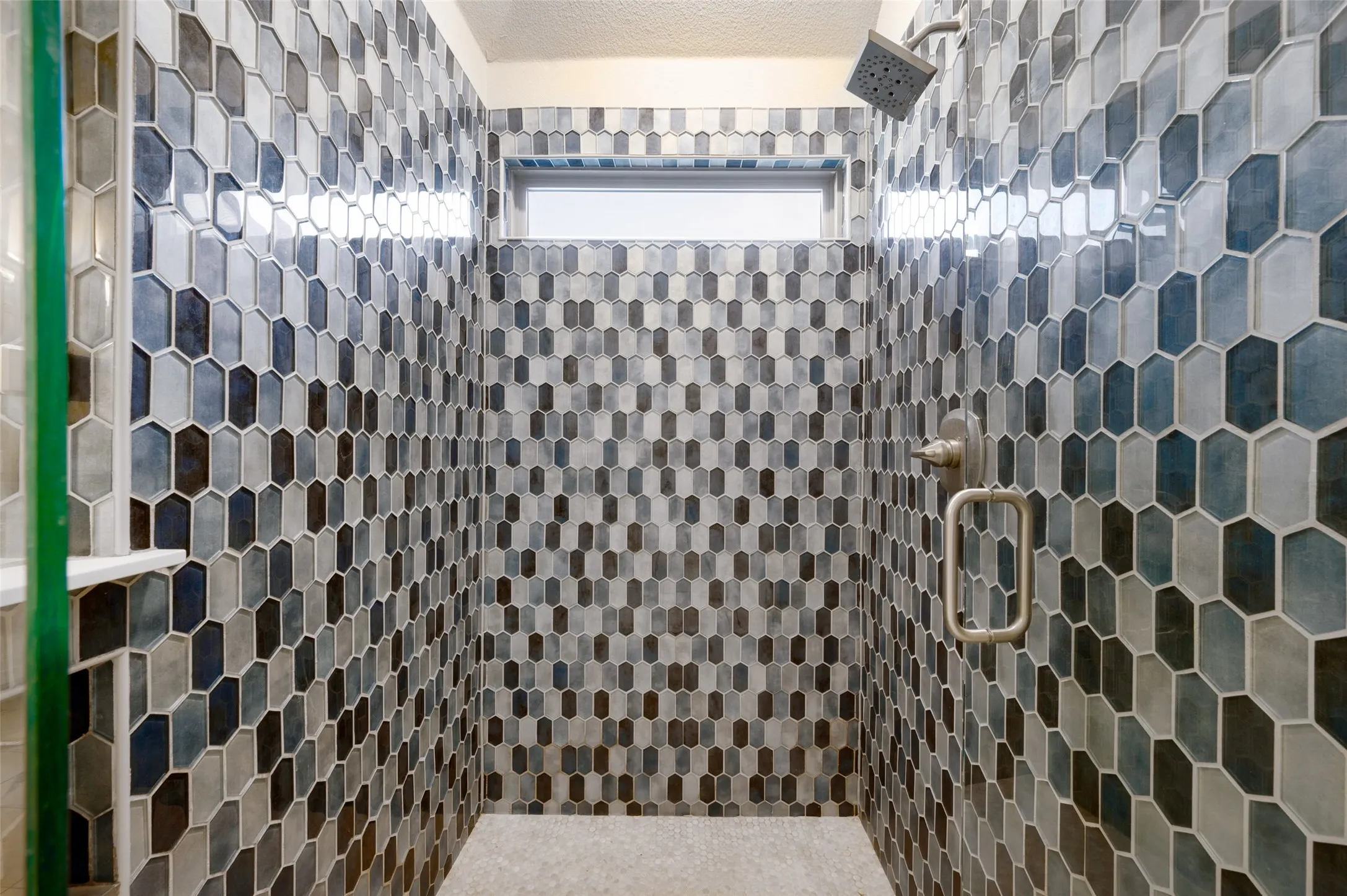 Walk-in shower featuring multi-tone geometric tile, built-in window, and a brushed nickel shower head