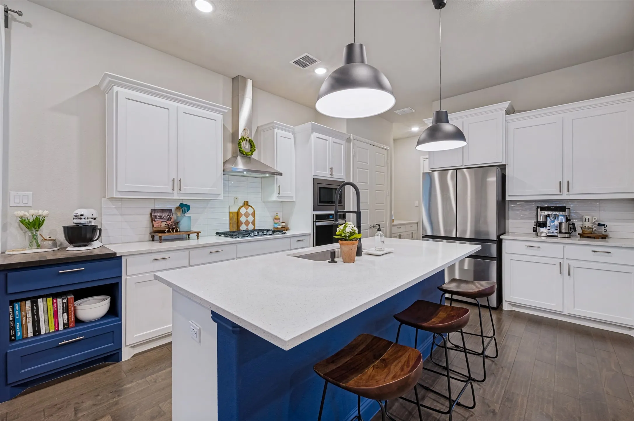 Spacious kitchen featuring white cabinetry, a large center island with seating, stainless steel appliances, and a tile backsplash