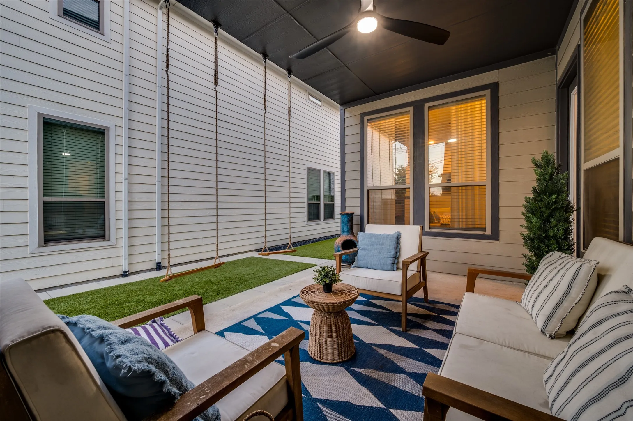 Covered patio with a ceiling fan, concrete flooring, and an artificial grass area