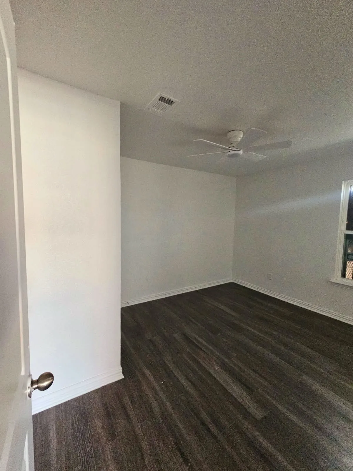 Wood-finish flooring with white baseboards and a ceiling fan