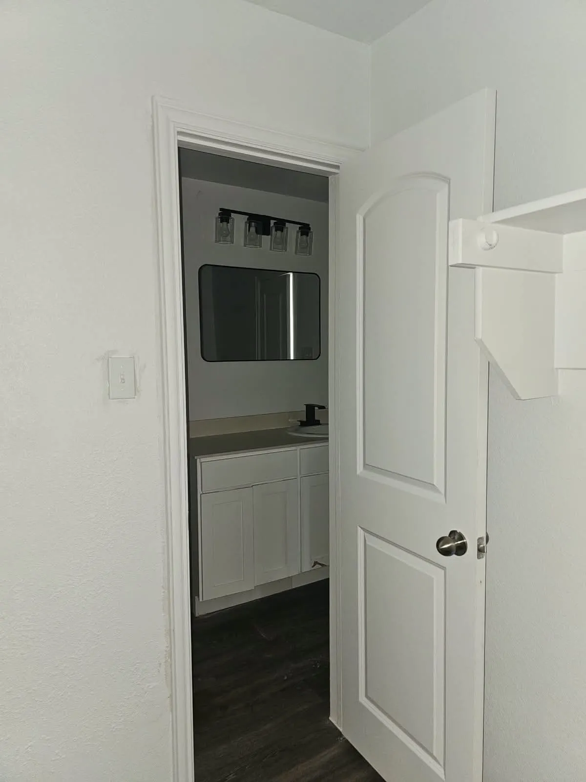 Bathroom featuring a single vanity with white cabinetry, light-toned countertop, and dark-finish faucet