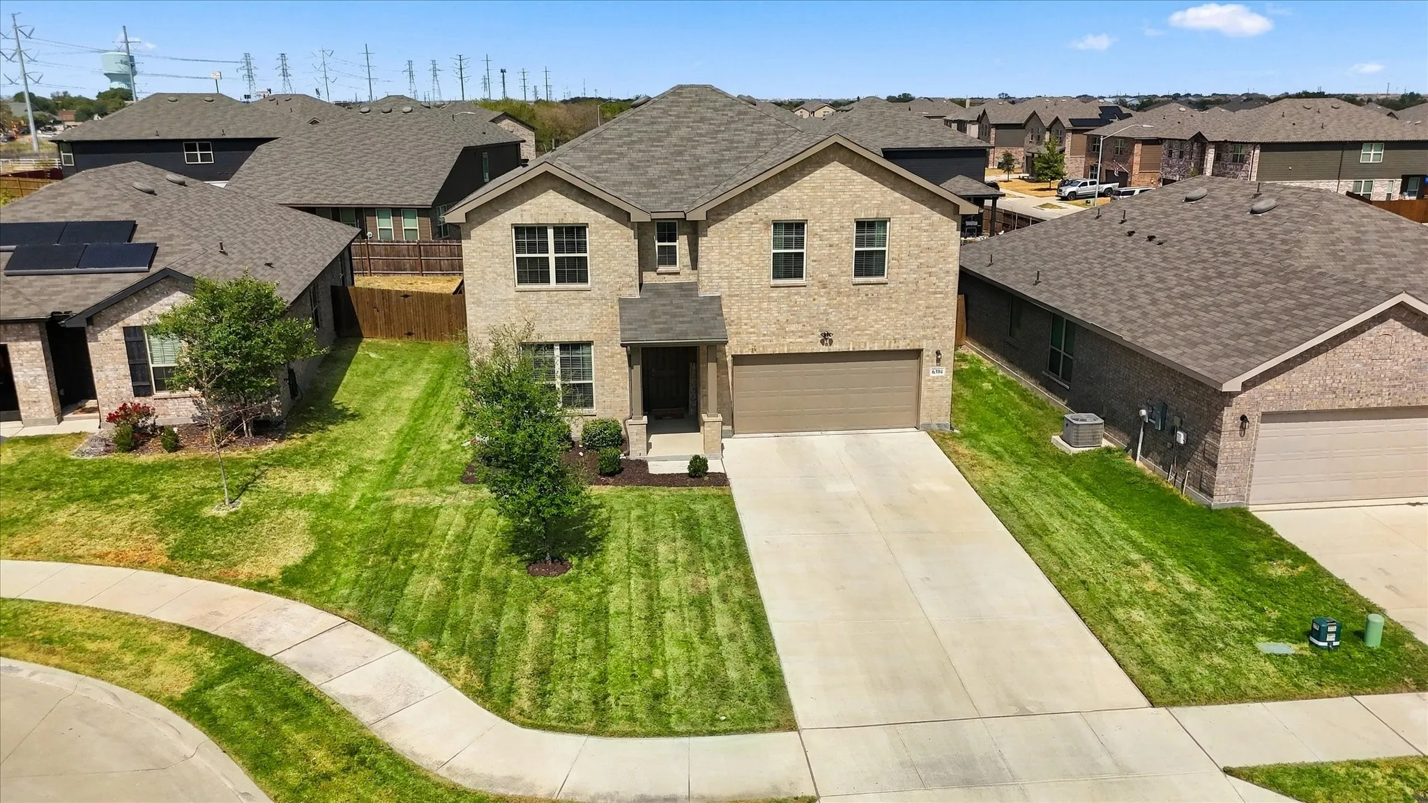 Two-story brick exterior with a two-car garage, concrete driveway, and front lawn