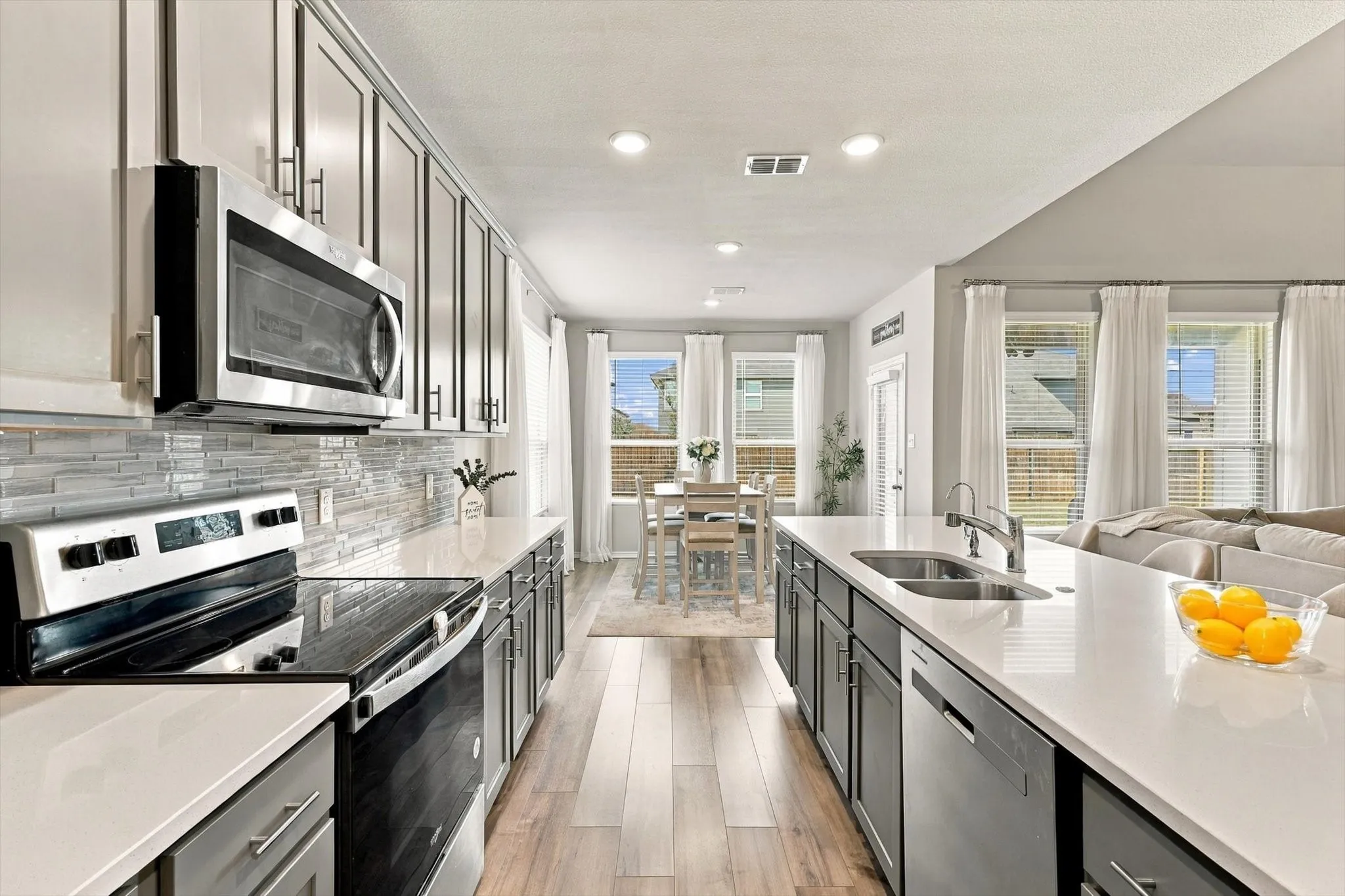 Gourmet kitchen featuring a large island, stainless steel appliances, crisp white countertops, and wood-finish flooring