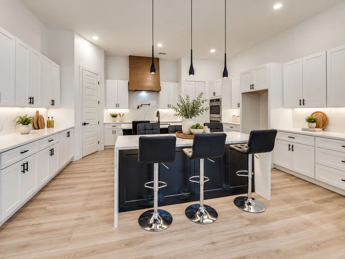 Modern kitchen featuring light wood-finish flooring, white cabinetry with matte black hardware, a dark island with a light-toned countertop, and recessed lighting