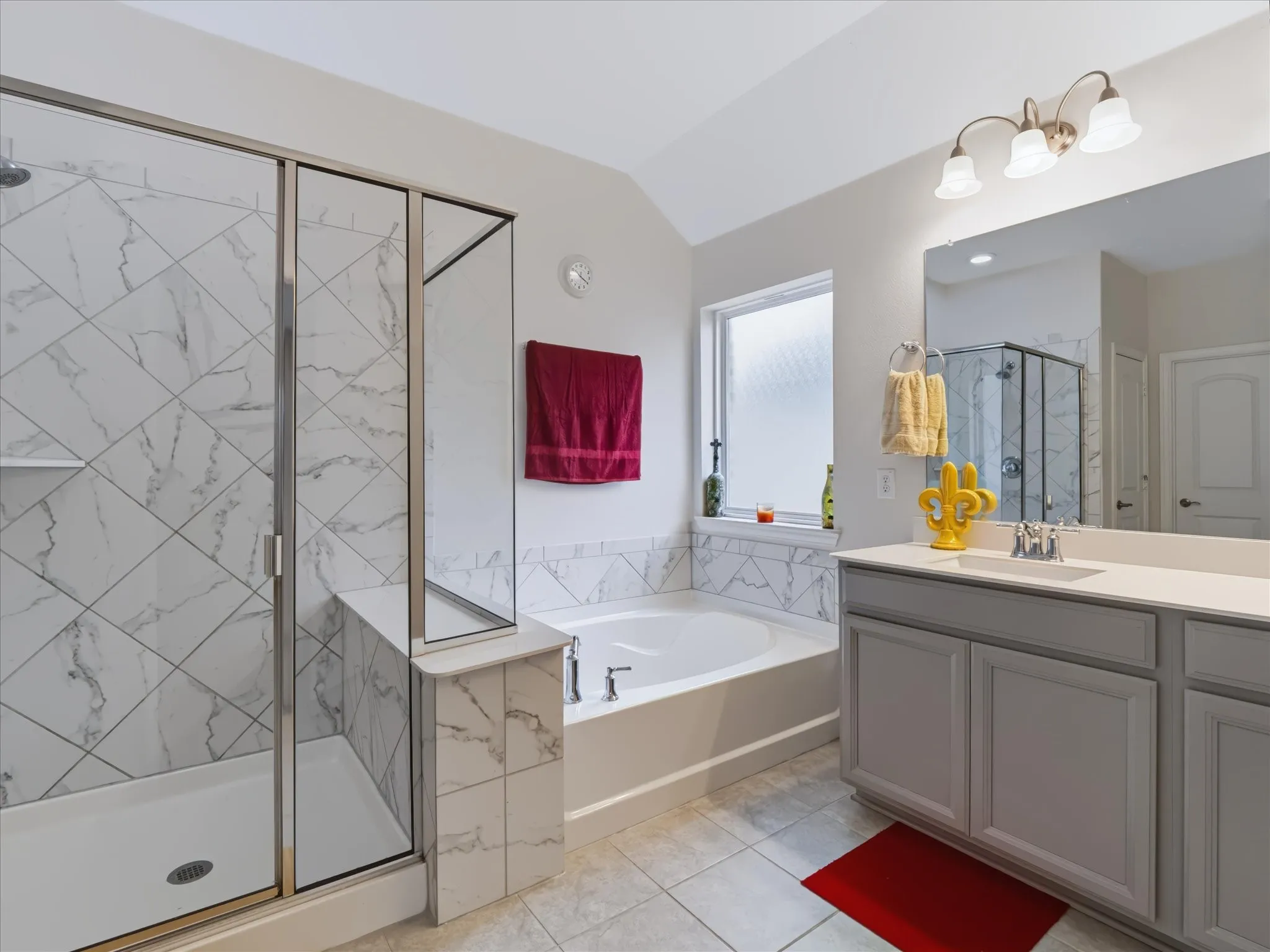 Walk-in shower with glass enclosure and marble-look tile surround