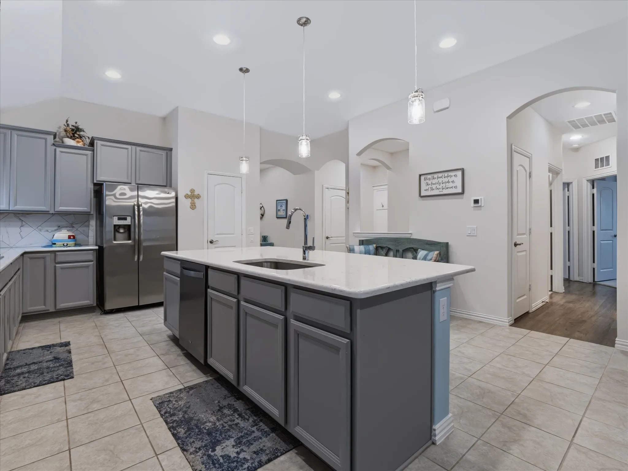 Kitchen featuring a central island with a sink, recessed lighting, tile flooring, and arched doorways