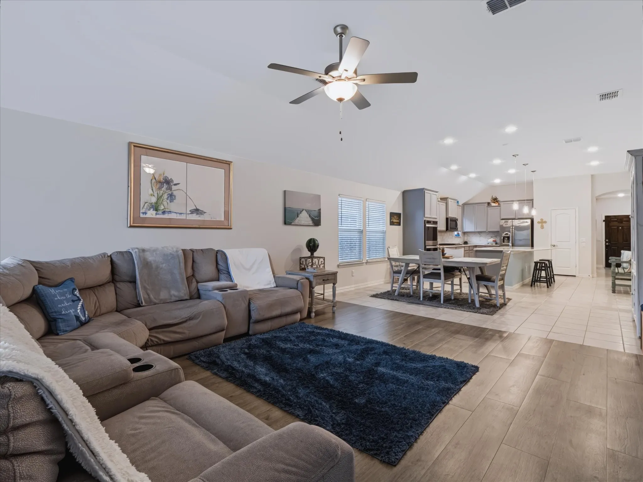 Vaulted ceiling with a ceiling fan, recessed lighting, wood-finish flooring, and a kitchen with built-in appliances