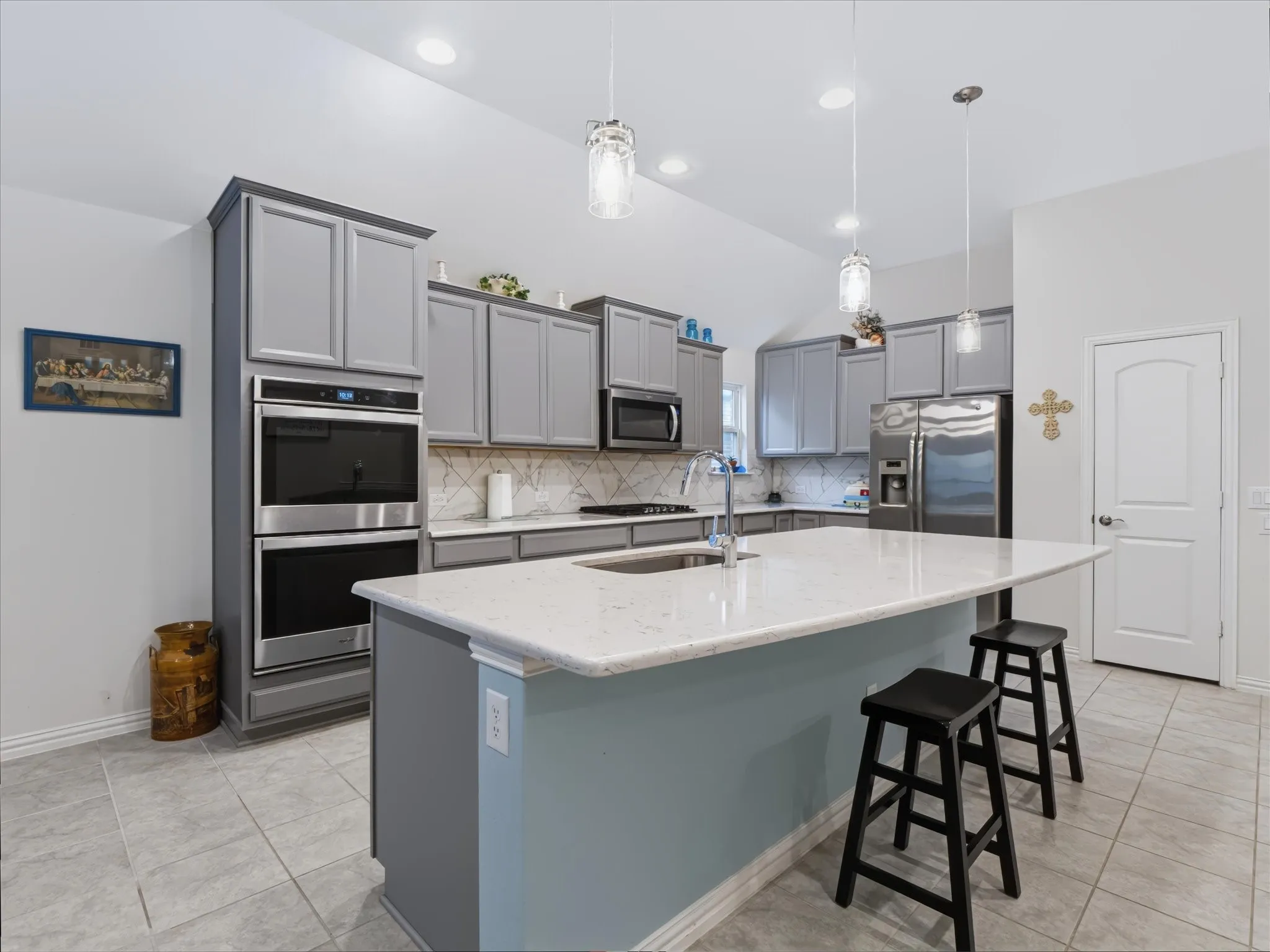 Kitchen featuring a center island with a stone countertop, recessed lighting, double wall ovens, a tile backsplash, and tile flooring