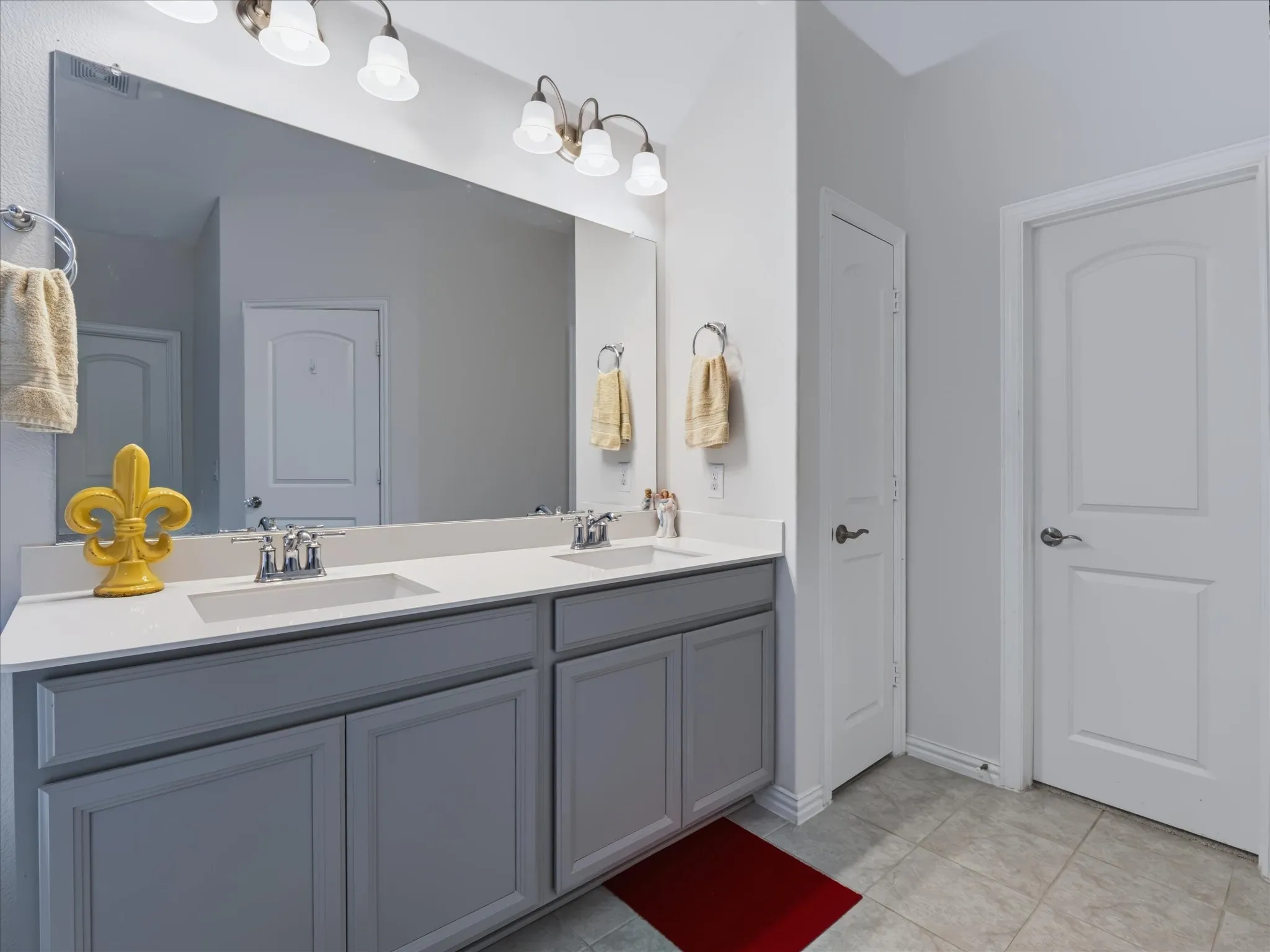 Dual vanity with gray cabinetry, white countertops, and chrome fixtures