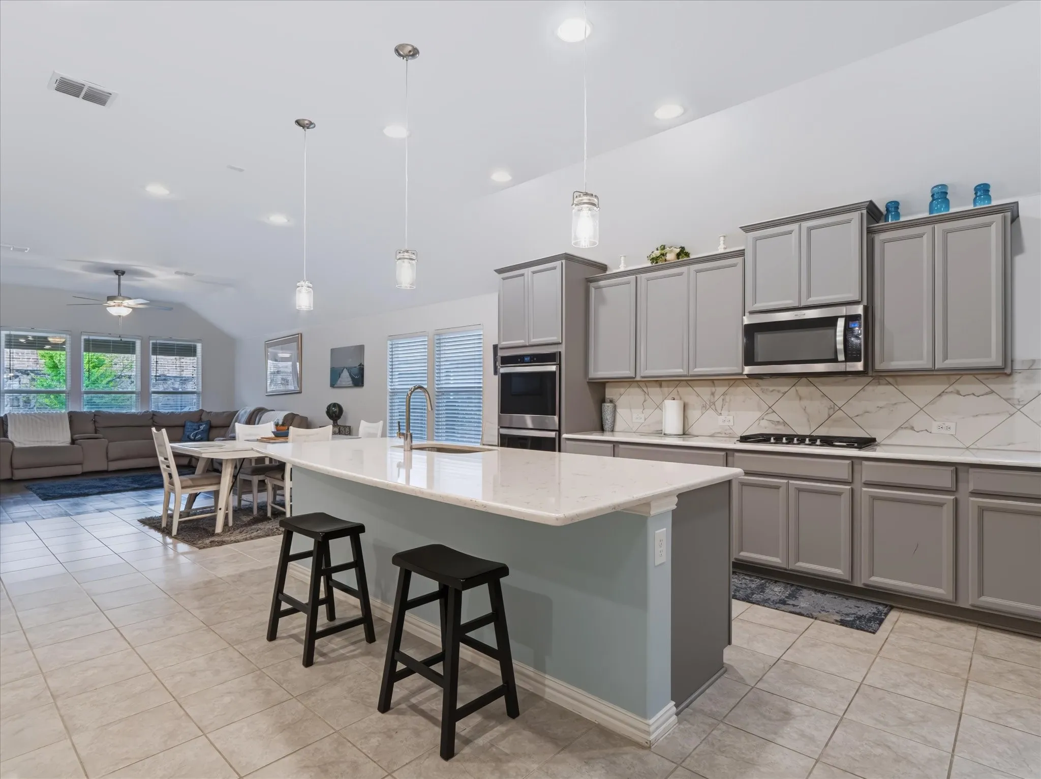 Open-concept kitchen featuring an island with a light-colored countertop, recessed lighting, tile flooring, and gray cabinetry